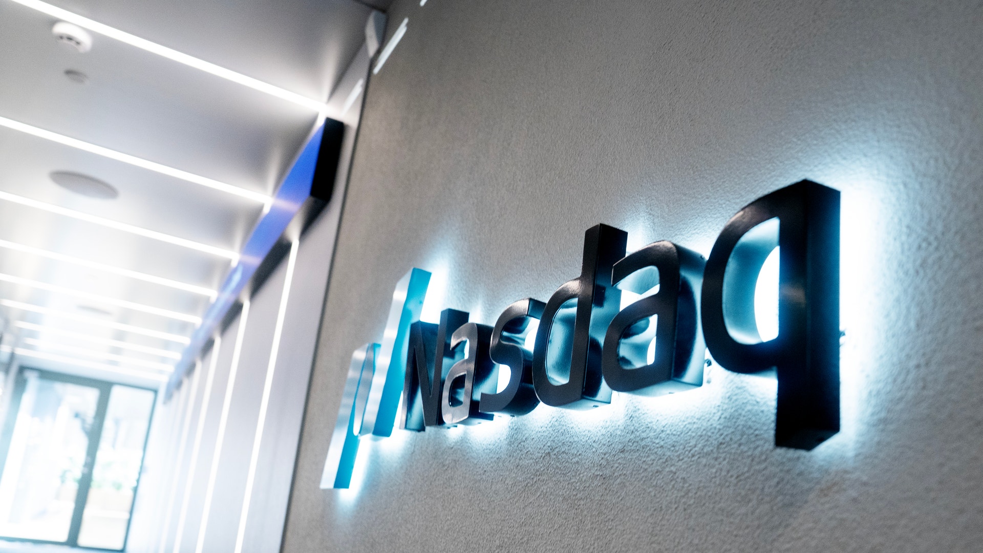 Nasdaqs logotyp på en vägg i en upplyst korridor.