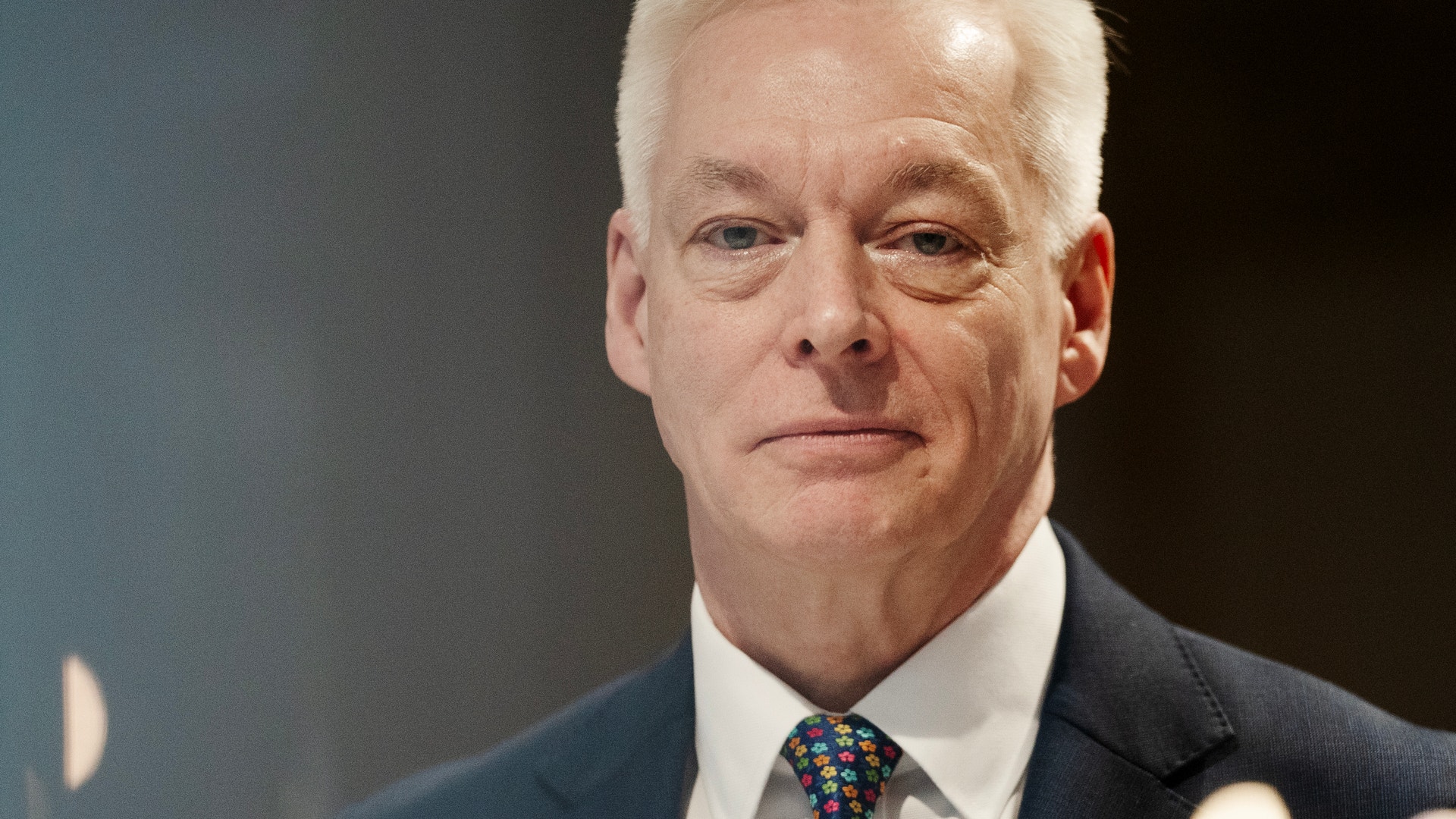 Porträttfoto av en man i mörk kostym och färgglad slips