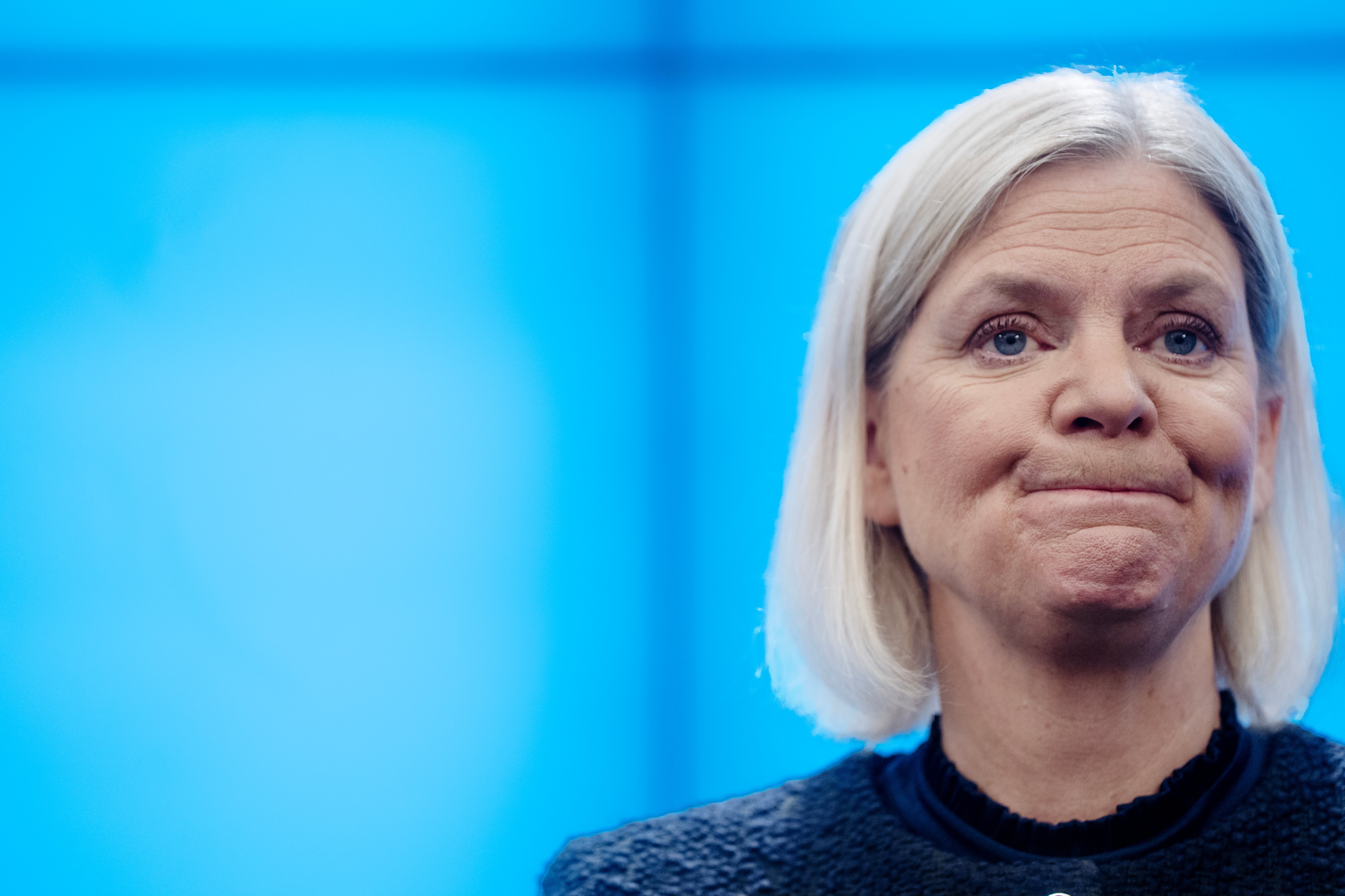 Porträtt av Magdalena Andersson med allvarlig min framför en blå bakgrund.