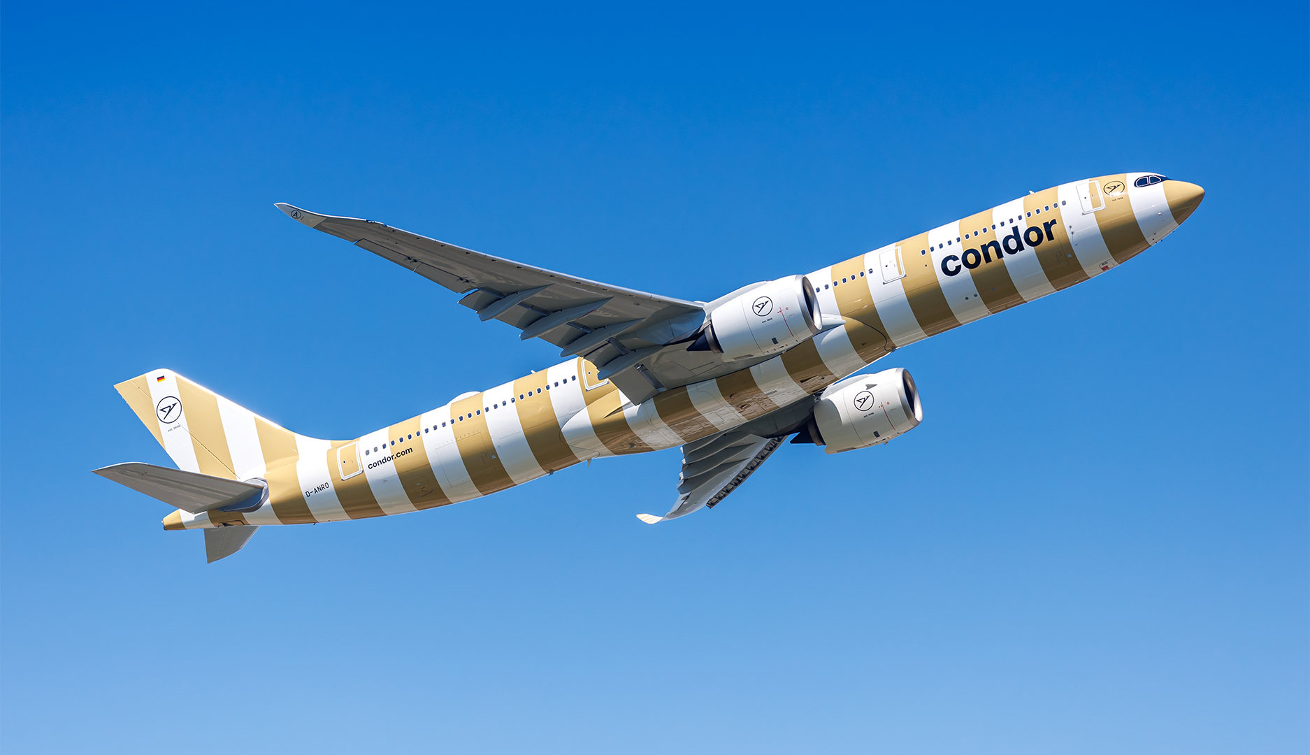 Ett Condor-flygplan i gul- och vitrandig färg flyger mot en klarblå himmel.