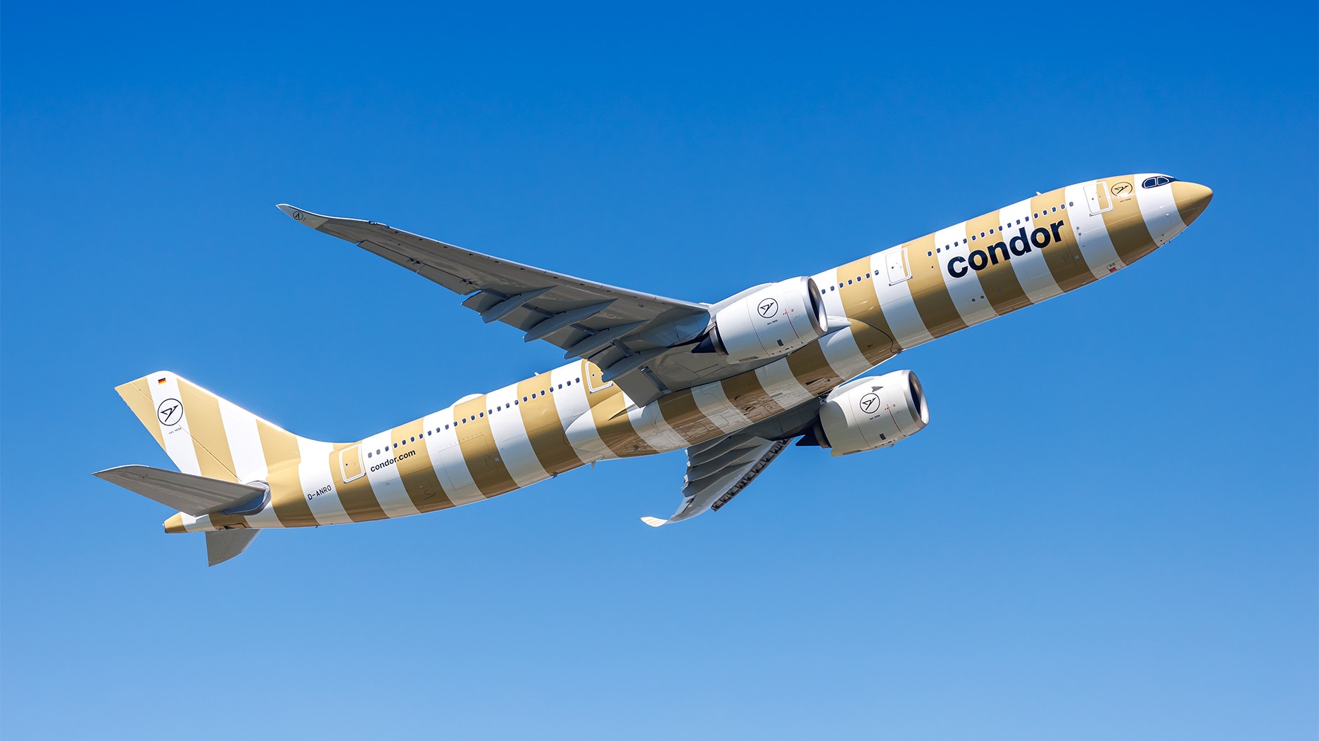 Ett Condor-flygplan i gul- och vitrandig färg flyger mot en klarblå himmel.