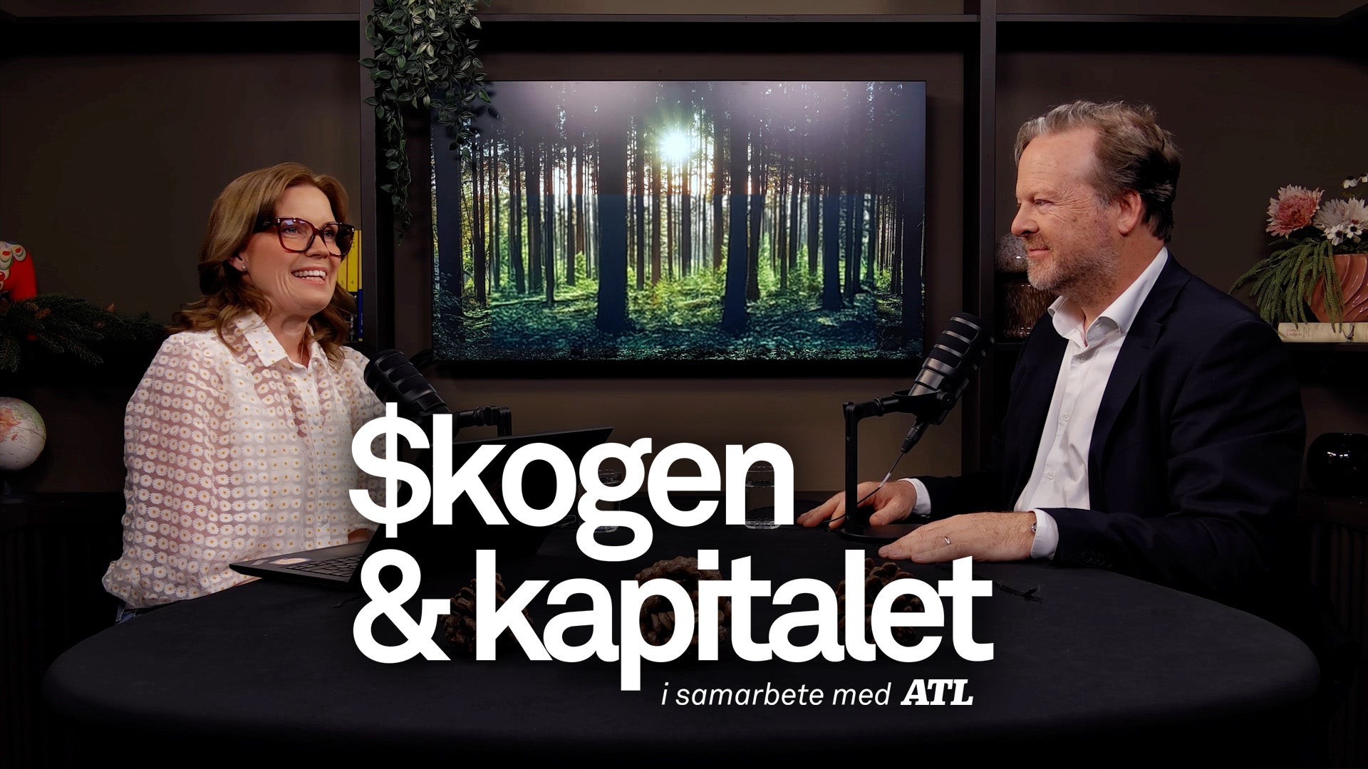 Två personer sitter och diskuterar i en studiomiljö med en skogsbild på en skärm bakom dem.