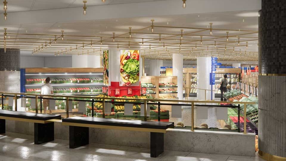 Interiörbild av en modern livsmedelsbutik med frukt- och grönsaksdiskar, dekorativa taklampor i guld och en person som handlar.