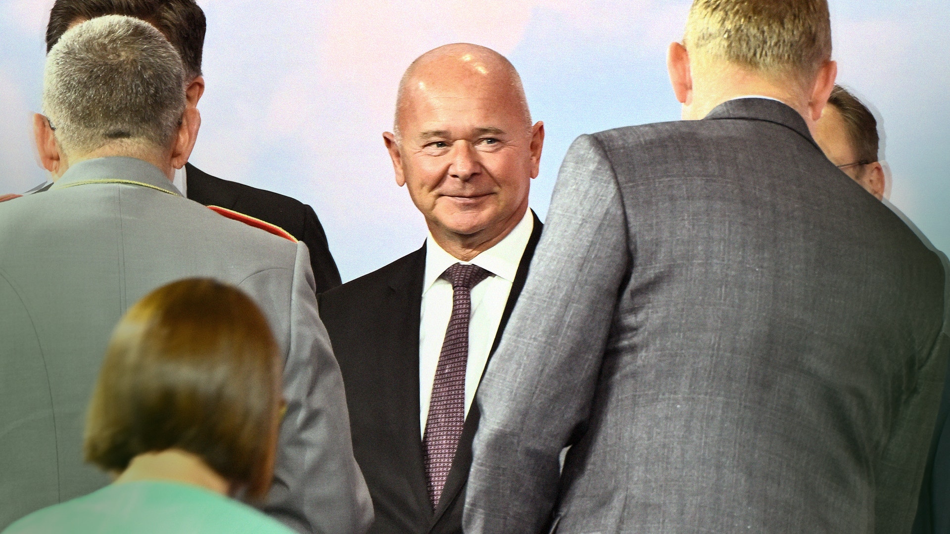 En grupp affärsmän i kostym och slips står tillsammans och samtalar.