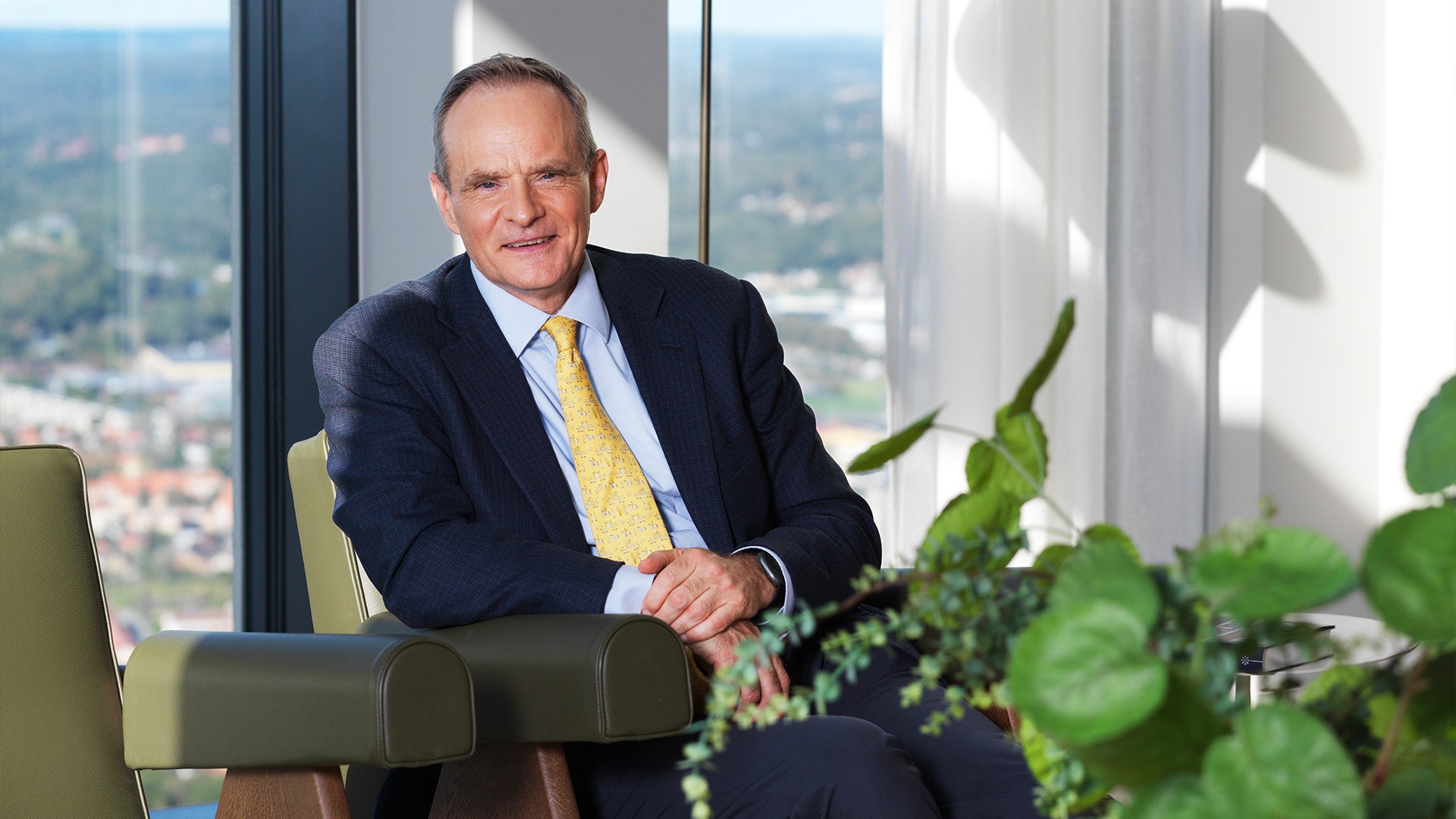 Simon Johnson sitter i kostym på en läderfåtölj. Han är i en ljus lägenhet i Göteborg.