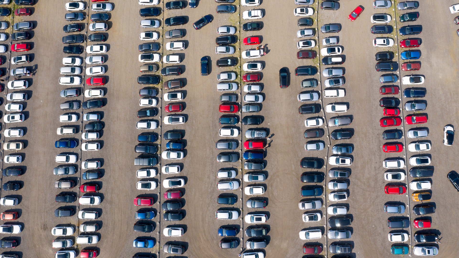 Flygfoto över en stor parkeringsplats med många bilar ordnade i rader