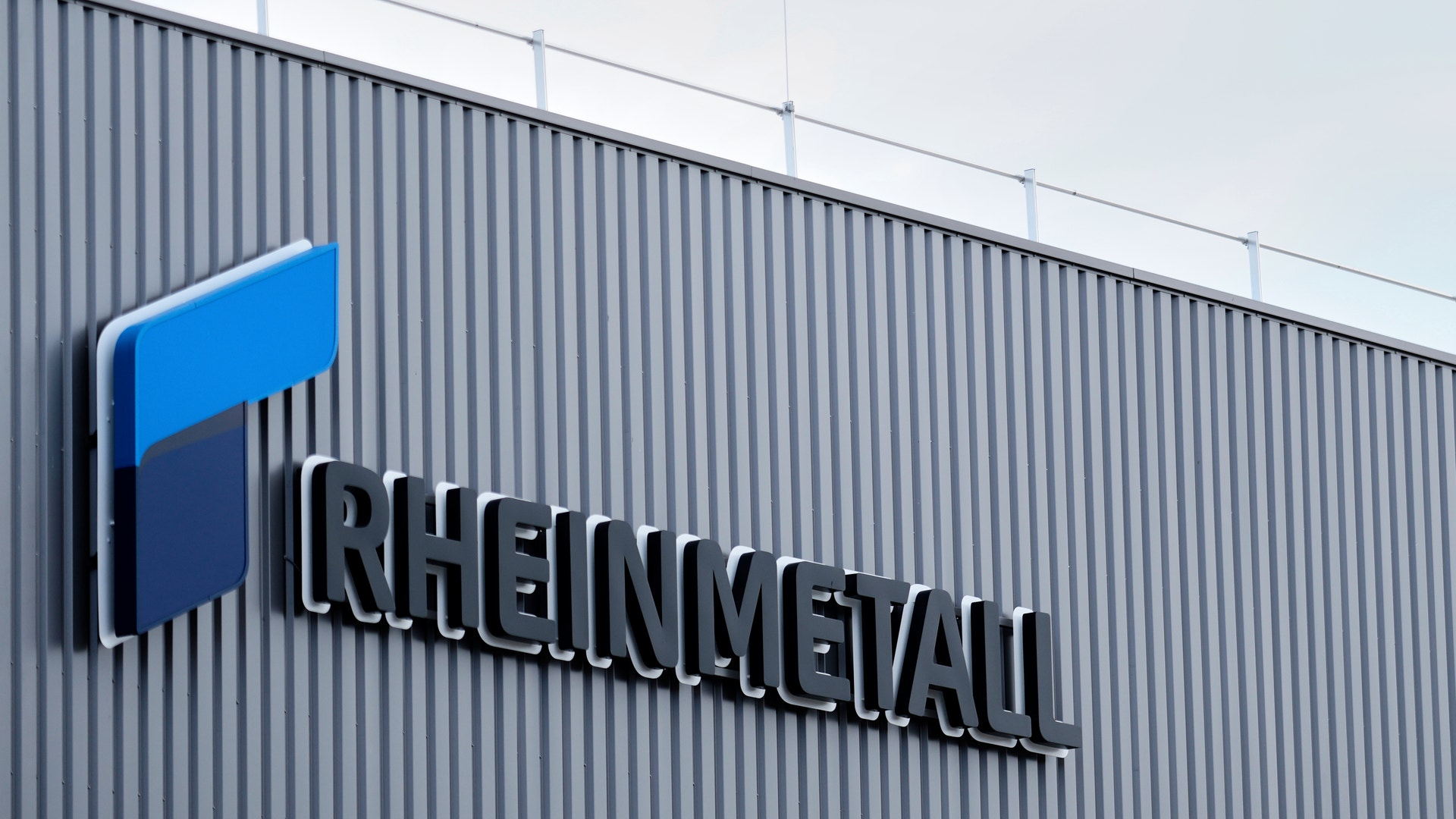 Företagslogga och namn på en industribyggnad med korrugerad metallvägg.