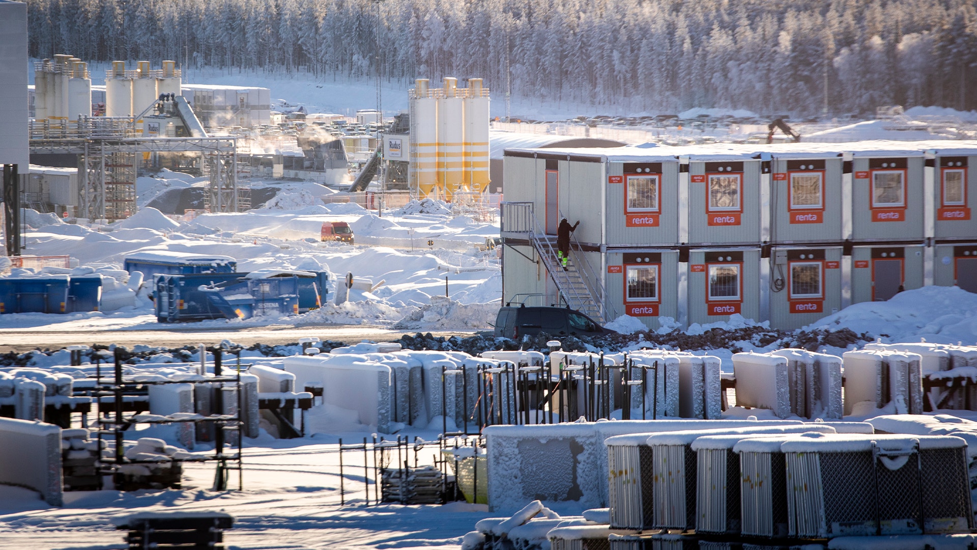 Industrianläggning i snölandskap med byggnader, containrar och utrustning.