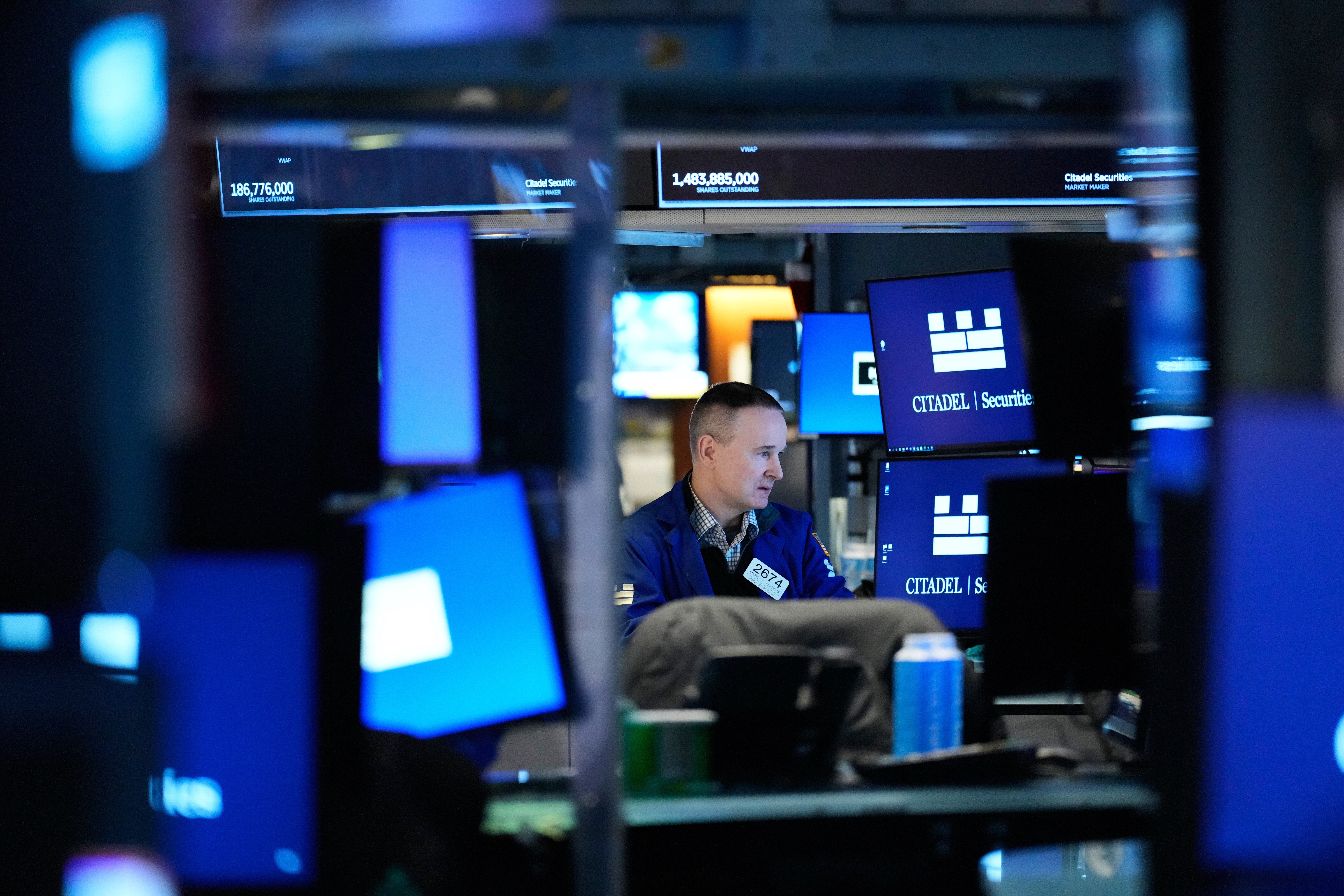 En man arbetar vid en datorskärm på ett modernt kontorsrum med blå belysning och flera övervakningsenheter.