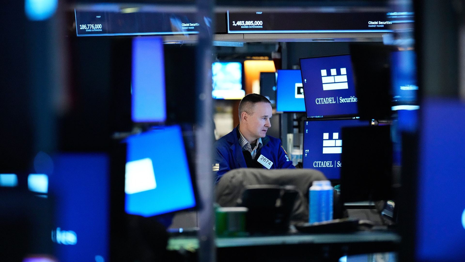 En man arbetar vid en datorskärm på ett modernt kontorsrum med blå belysning och flera övervakningsenheter.