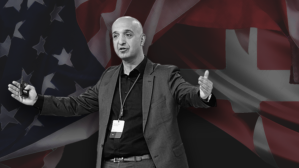 En man ger en presentation framför amerikanska och kanadensiska flaggor