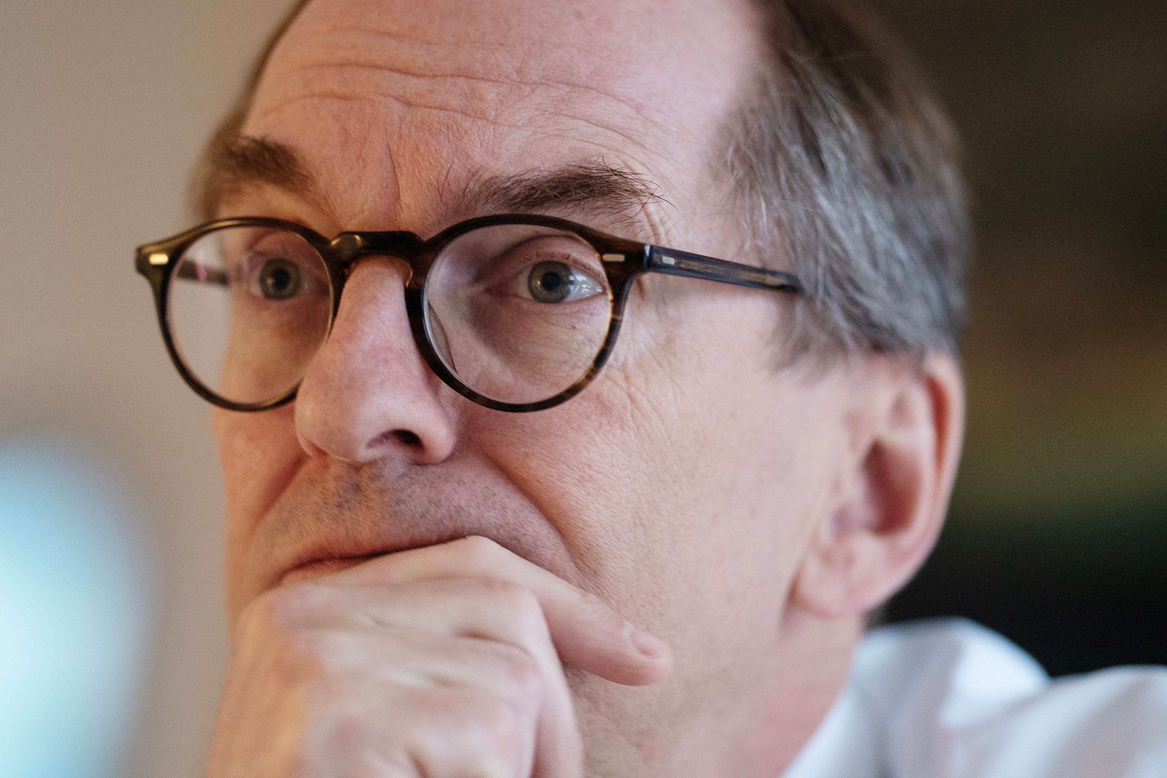 Porträttfoto av en man med glasögon i en tankfull pose