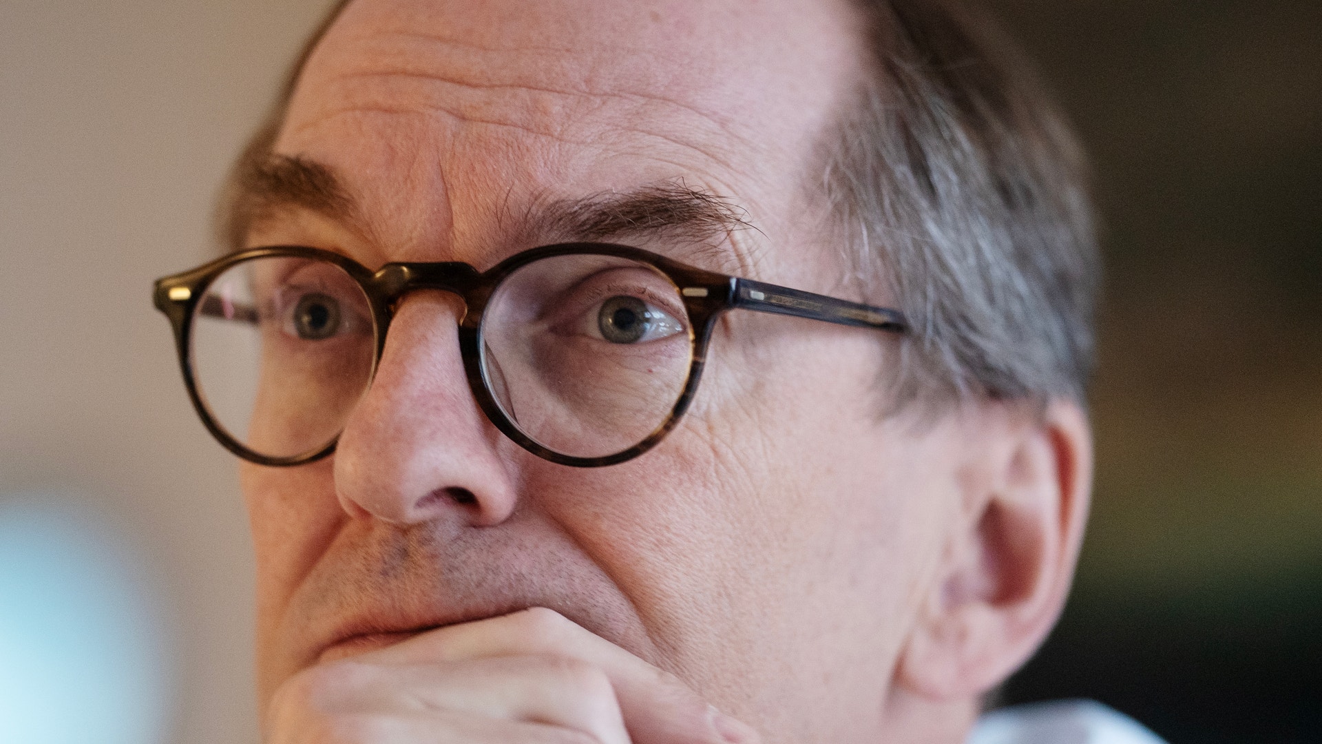 Porträttfoto av en man med glasögon i en tankfull pose