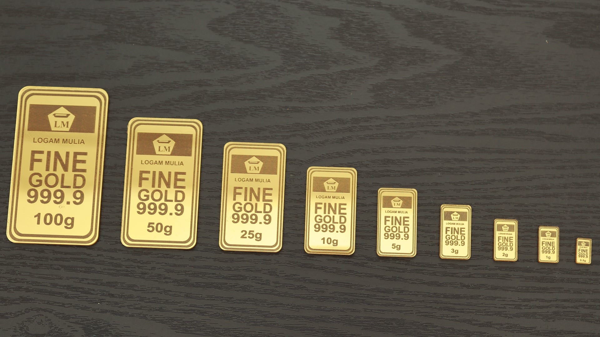 Rad av guldtackor i olika storlekar, från större till mindre, på en mörk träyta.