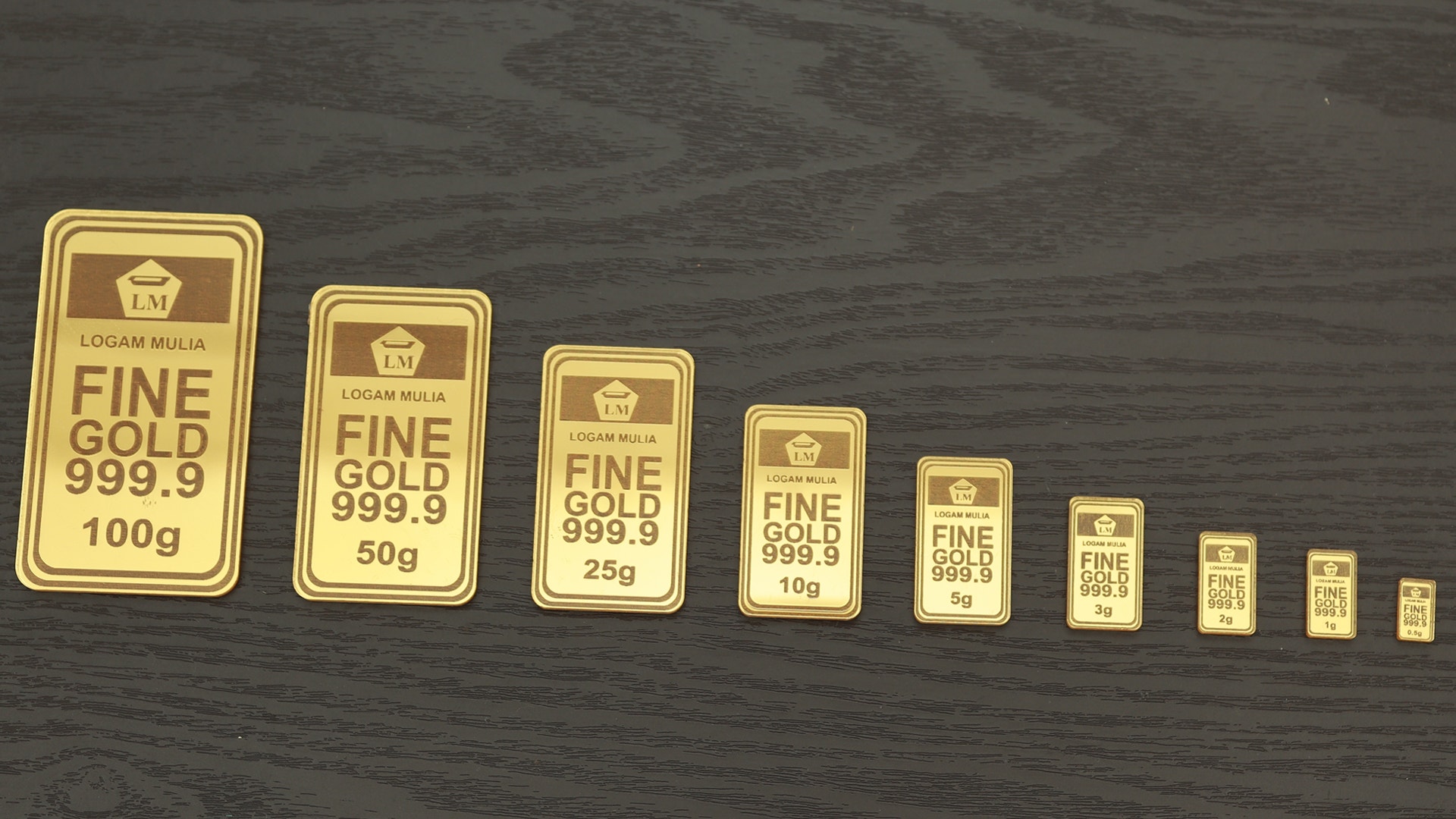 Rad av guldtackor i olika storlekar, från större till mindre, på en mörk träyta.