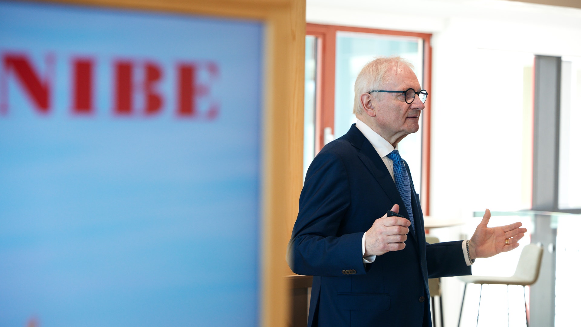 Man i mörkblå kostym håller presentation framför blå vägg med NIBE-logga.