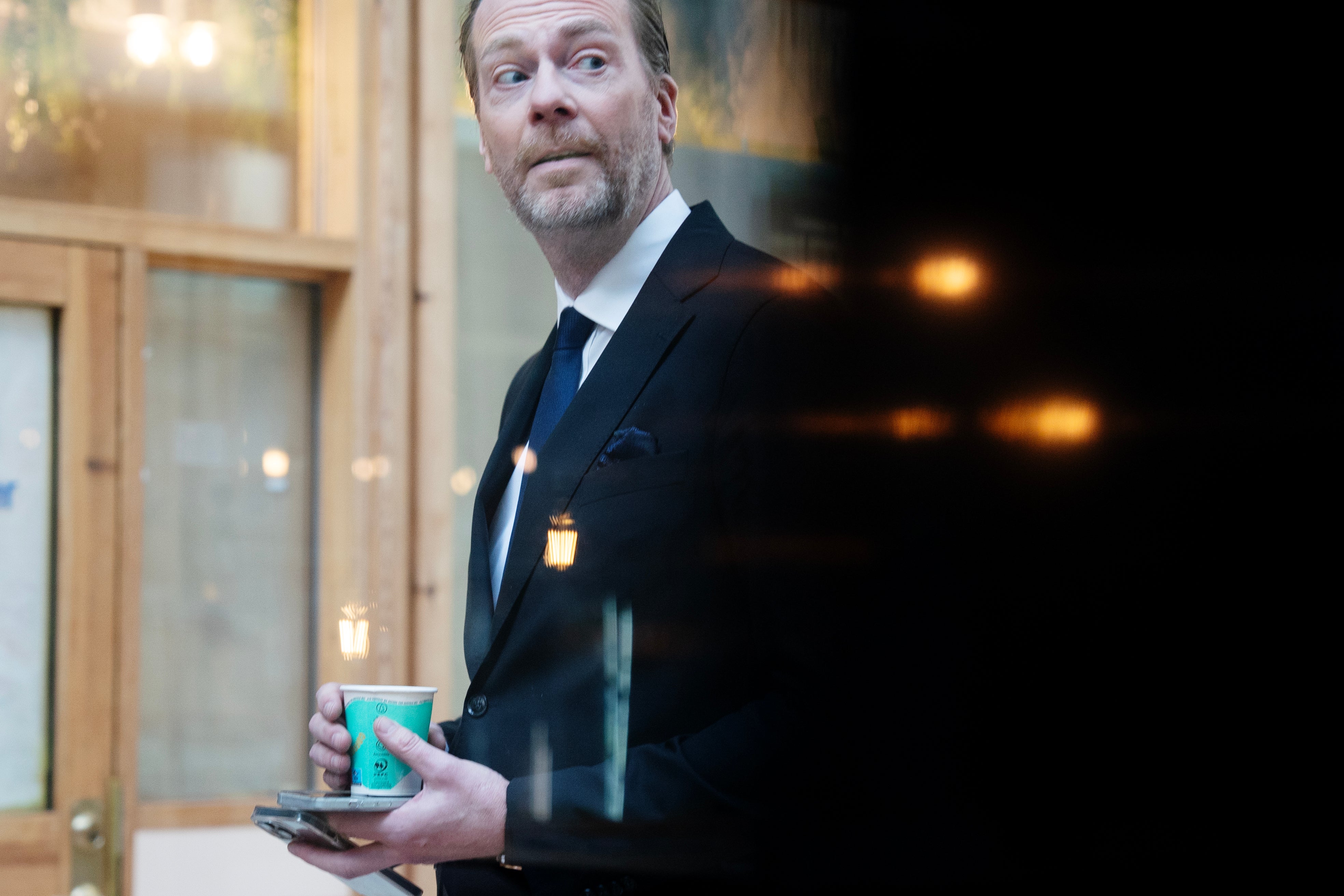 Porträtt av en man i kostym som håller en dryck