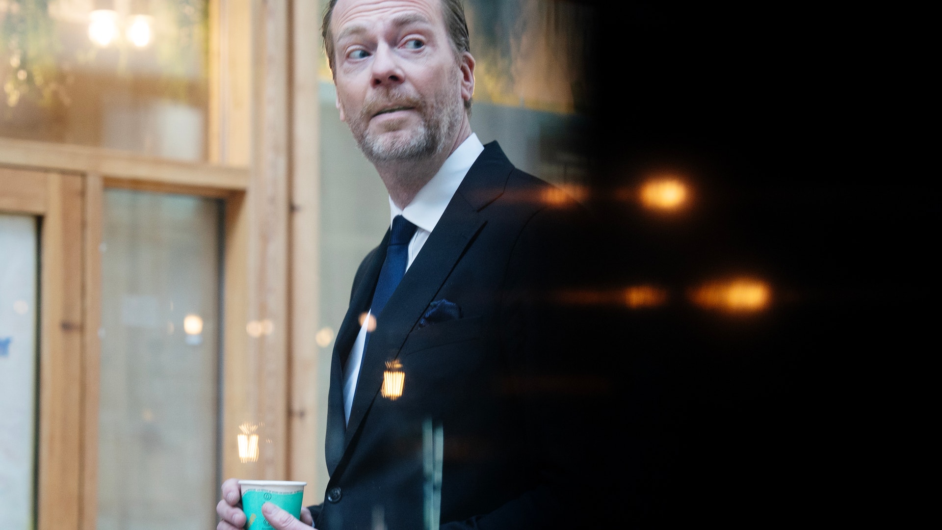 Porträtt av en man i kostym som håller en dryck