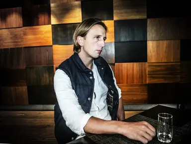 En person sitter vid ett bord framför en vägg med geometriska träpaneler i olika nyanser.