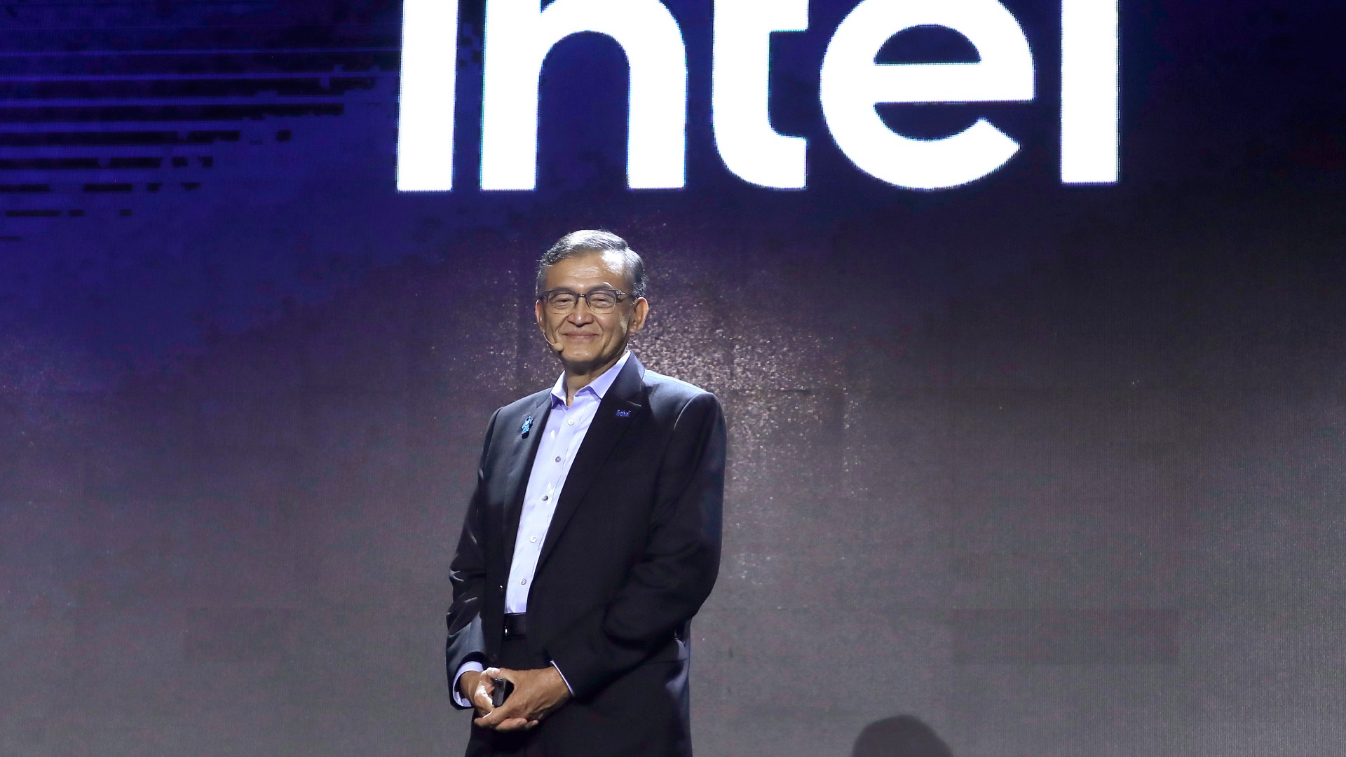 Man i kostym presenterar på scen framför Intel-logotyp