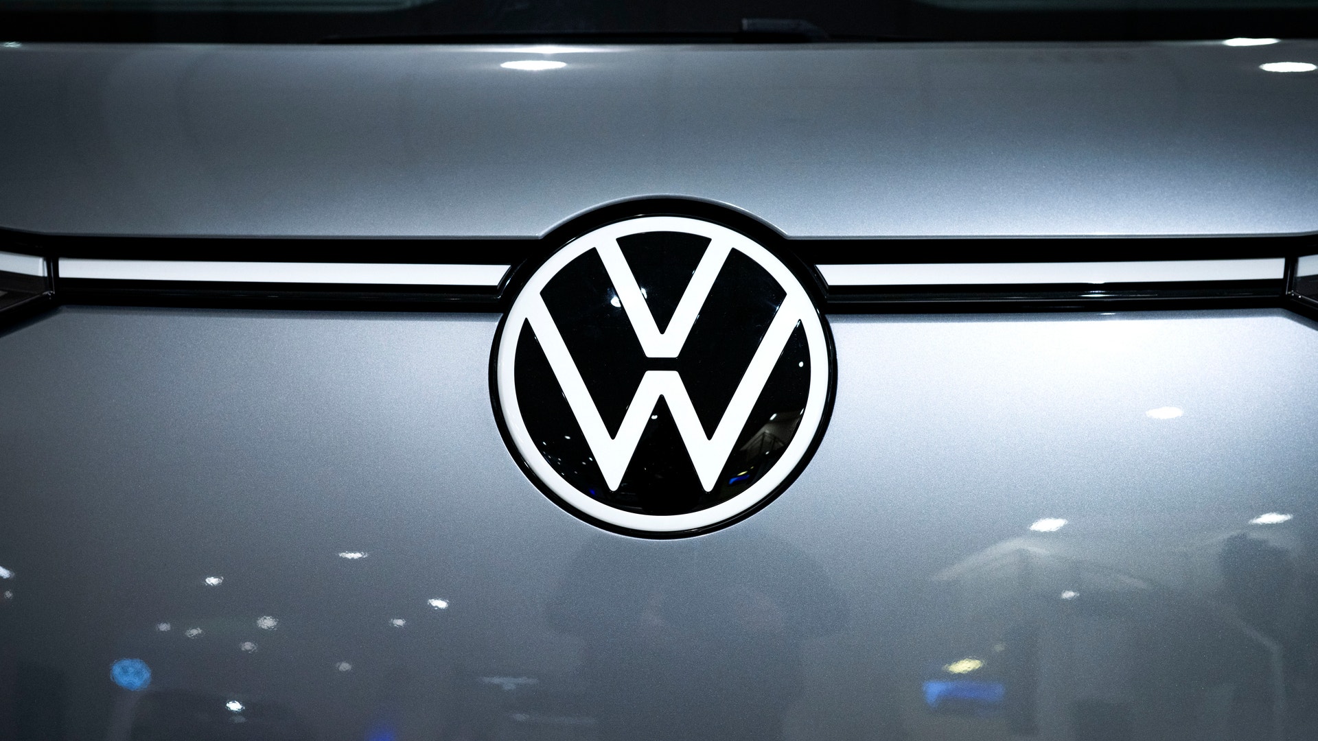 Volkswagens logotyp på en bil. En vit cirkel med VW-bokstäver på en mörkgrå bilfront.