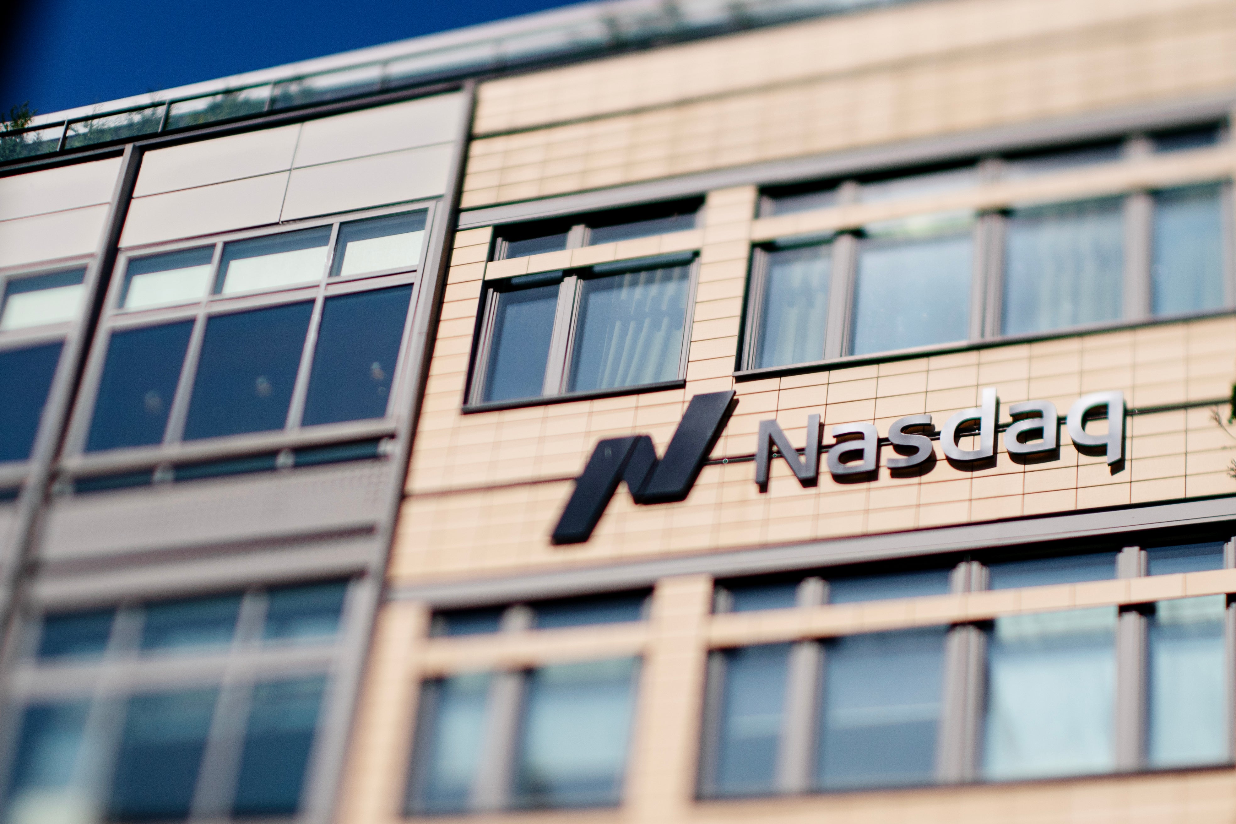 Nasdaq-logon på fasaden av en modern kontorsbyggnad med ljusa väggar och många fönster.