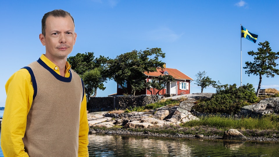 Philip Warkander framför en klassisk röd sommarstuga med vita knutar, belägen på en ö.