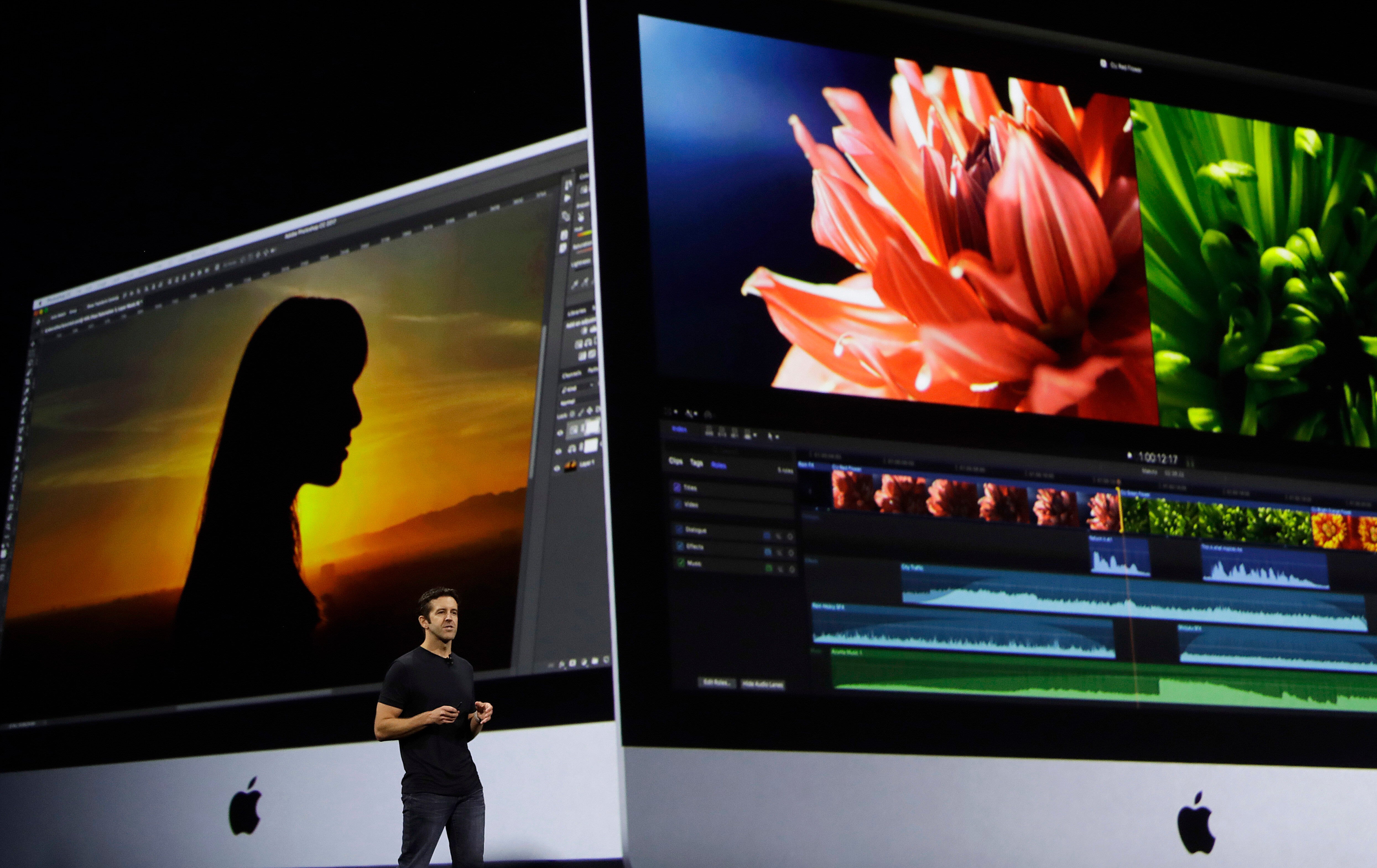 En person presenterar videoedigeringsprogram på två stora Apple iMac-skärmar. Den vänstra skärmen visar en silhuett mot solnedgång, den högra visar en blomma med videoredigeringsverktyg.