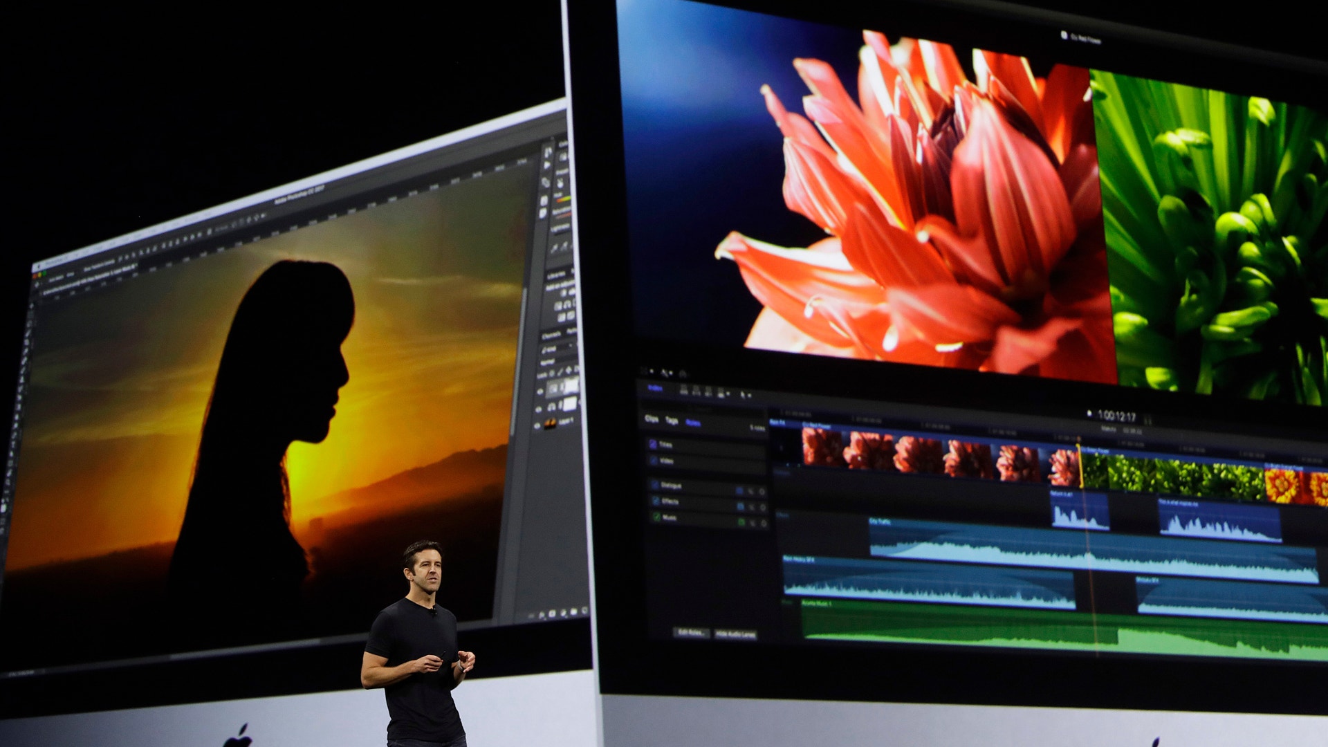 En person presenterar videoedigeringsprogram på två stora Apple iMac-skärmar. Den vänstra skärmen visar en silhuett mot solnedgång, den högra visar en blomma med videoredigeringsverktyg.