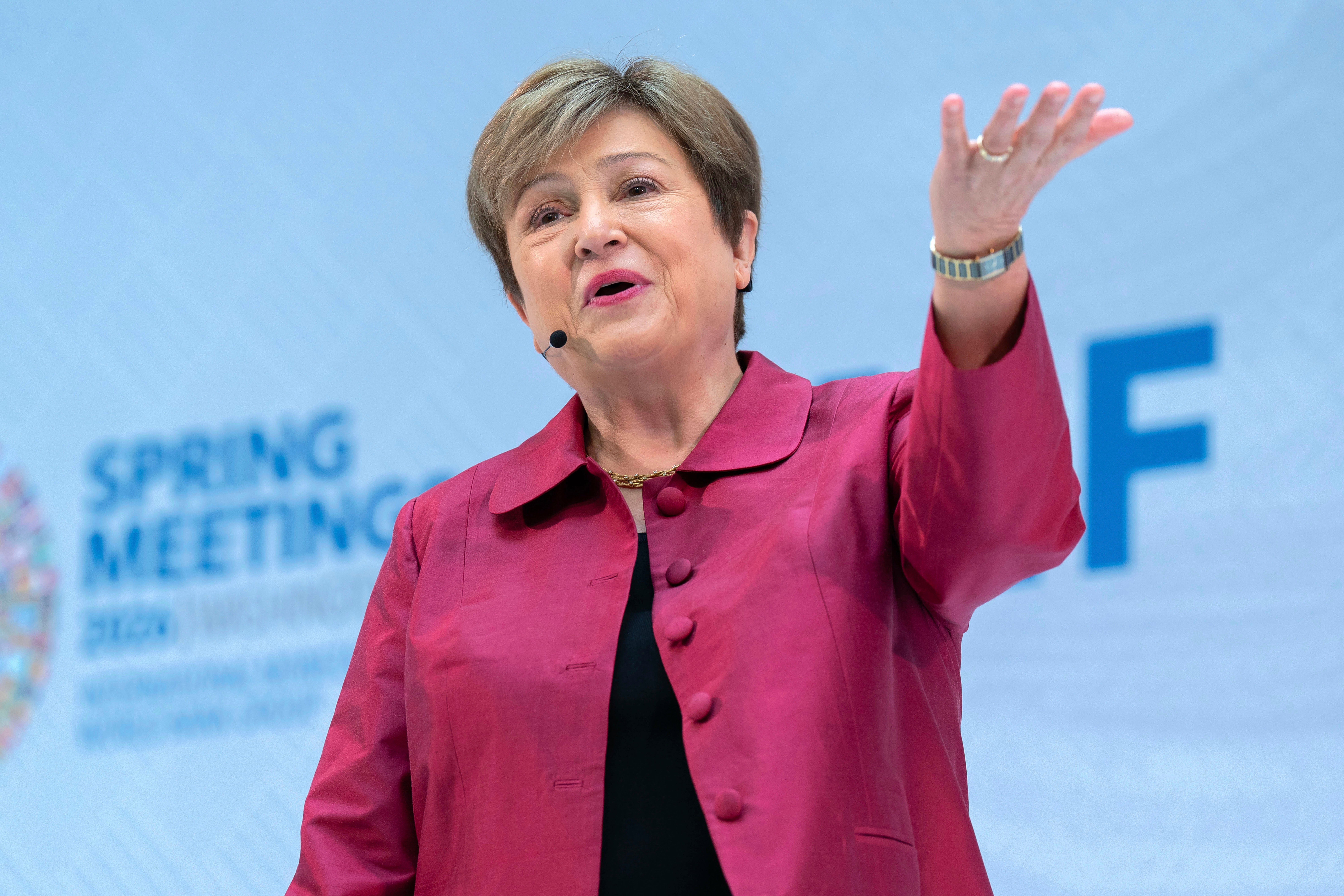 En kvinna i rosa jacka håller ett tal på en konferens och gestikulerar medan hon talar.