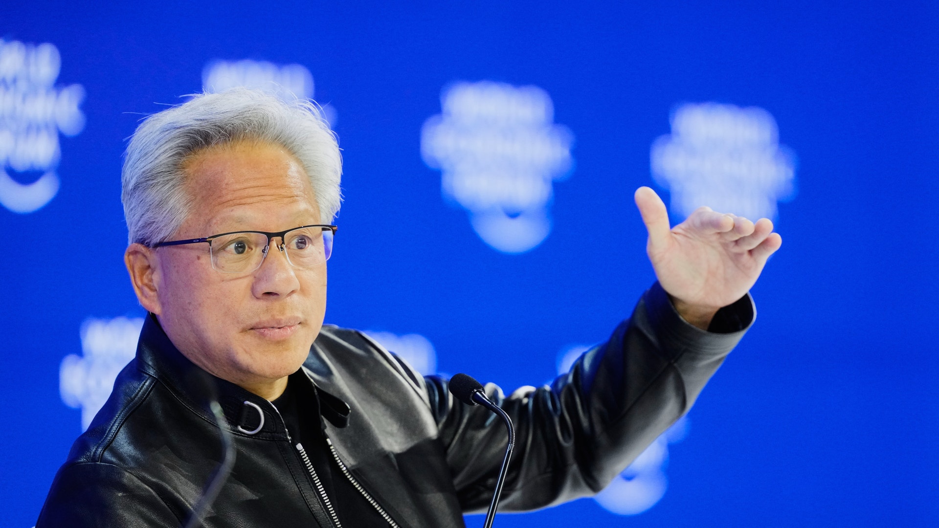 Nvidias vd Jensen Huang i svart läderiacka gestikulerar medan han talar mot blå bakgrund