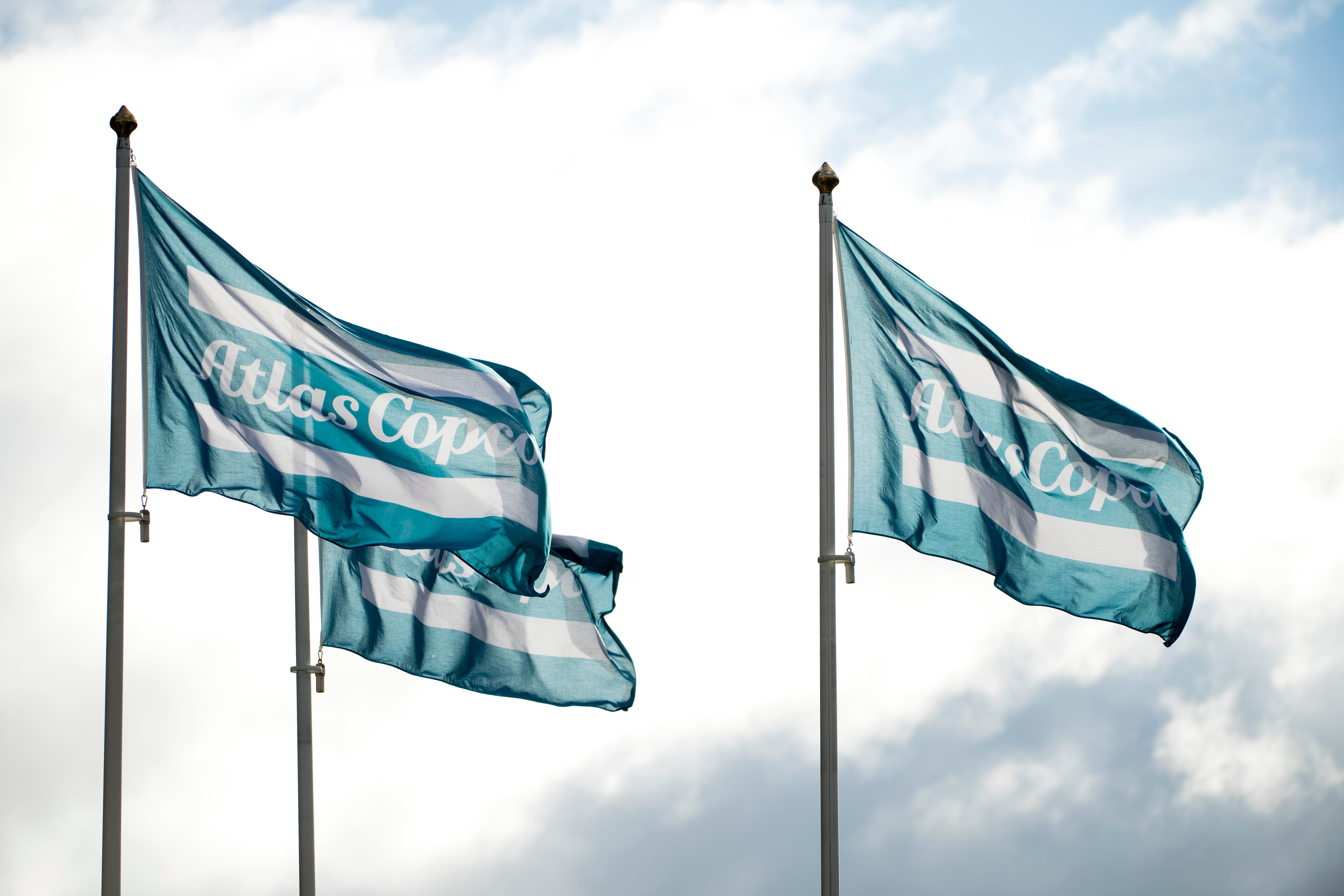 Två teal- och vitrandiga flaggor som vajar mot en molnig himmel