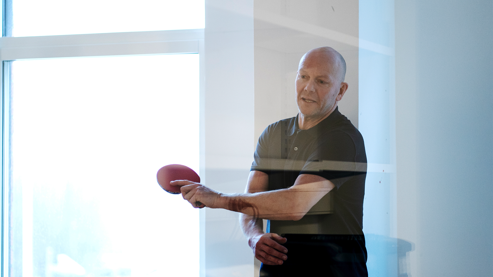 Mats Sundin står med ett rött pingisracket i handen och har precis slagit iväg en boll.