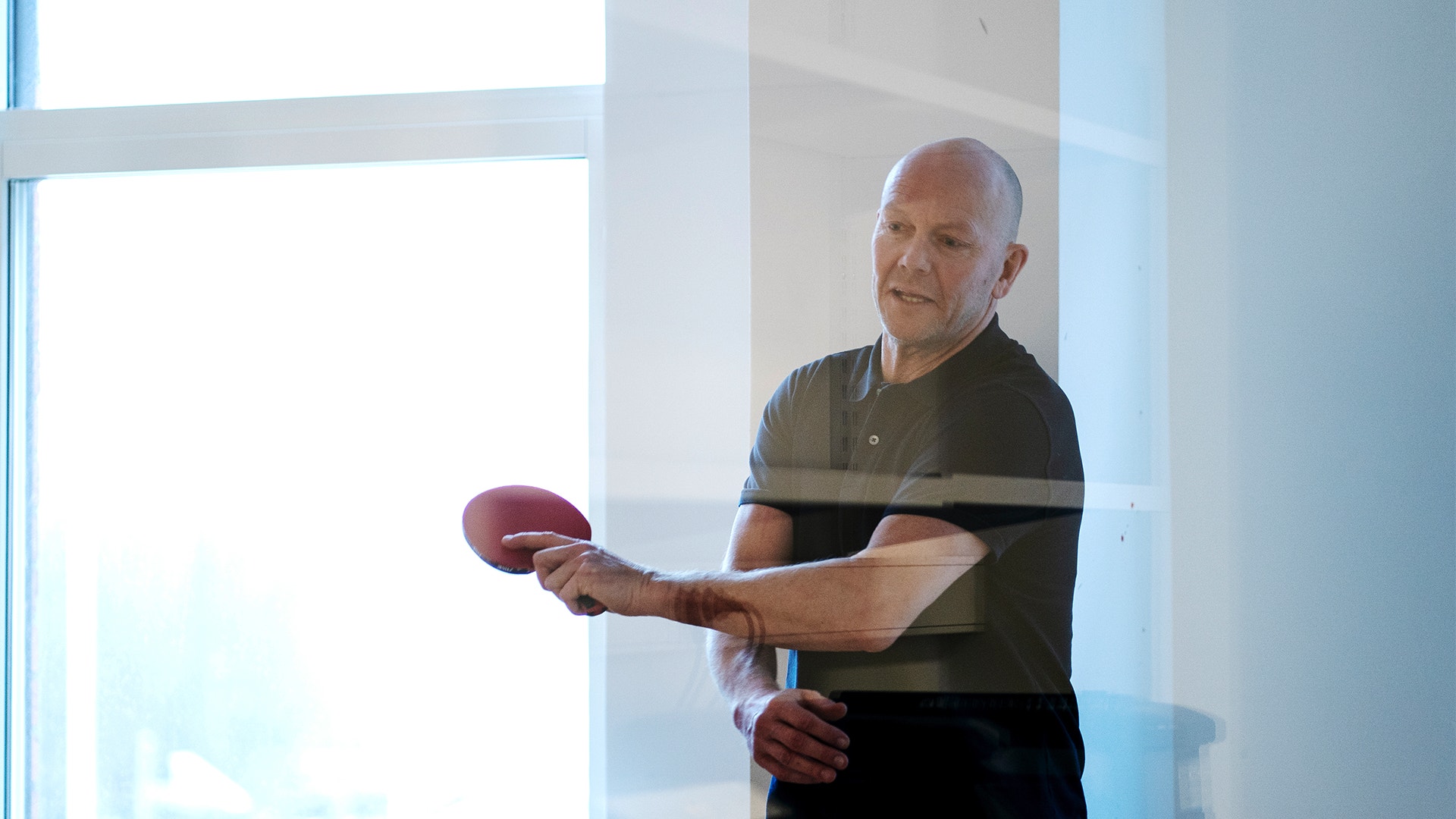 Mats Sundin står med ett rött pingisracket i handen och har precis slagit iväg en boll.