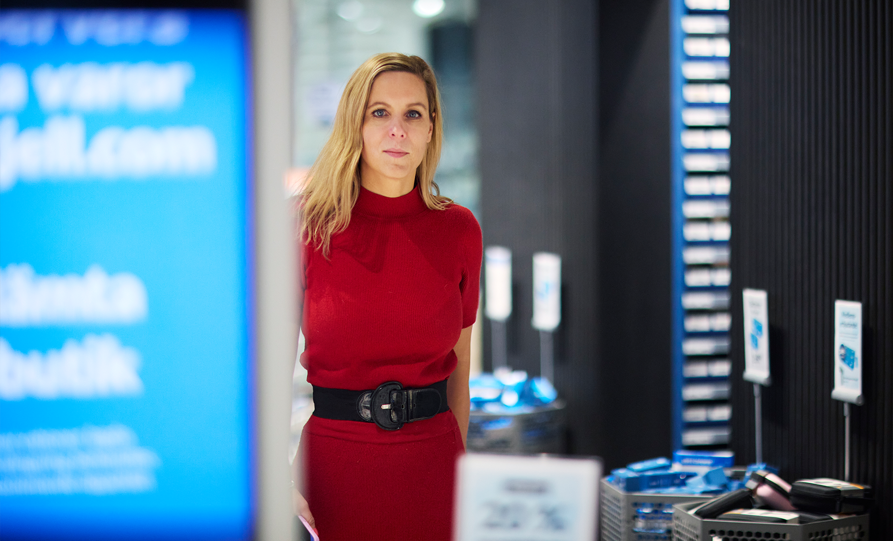 Porträtt av en kvinna i röd tröja i en modern kontorsmiljö med blå belysning