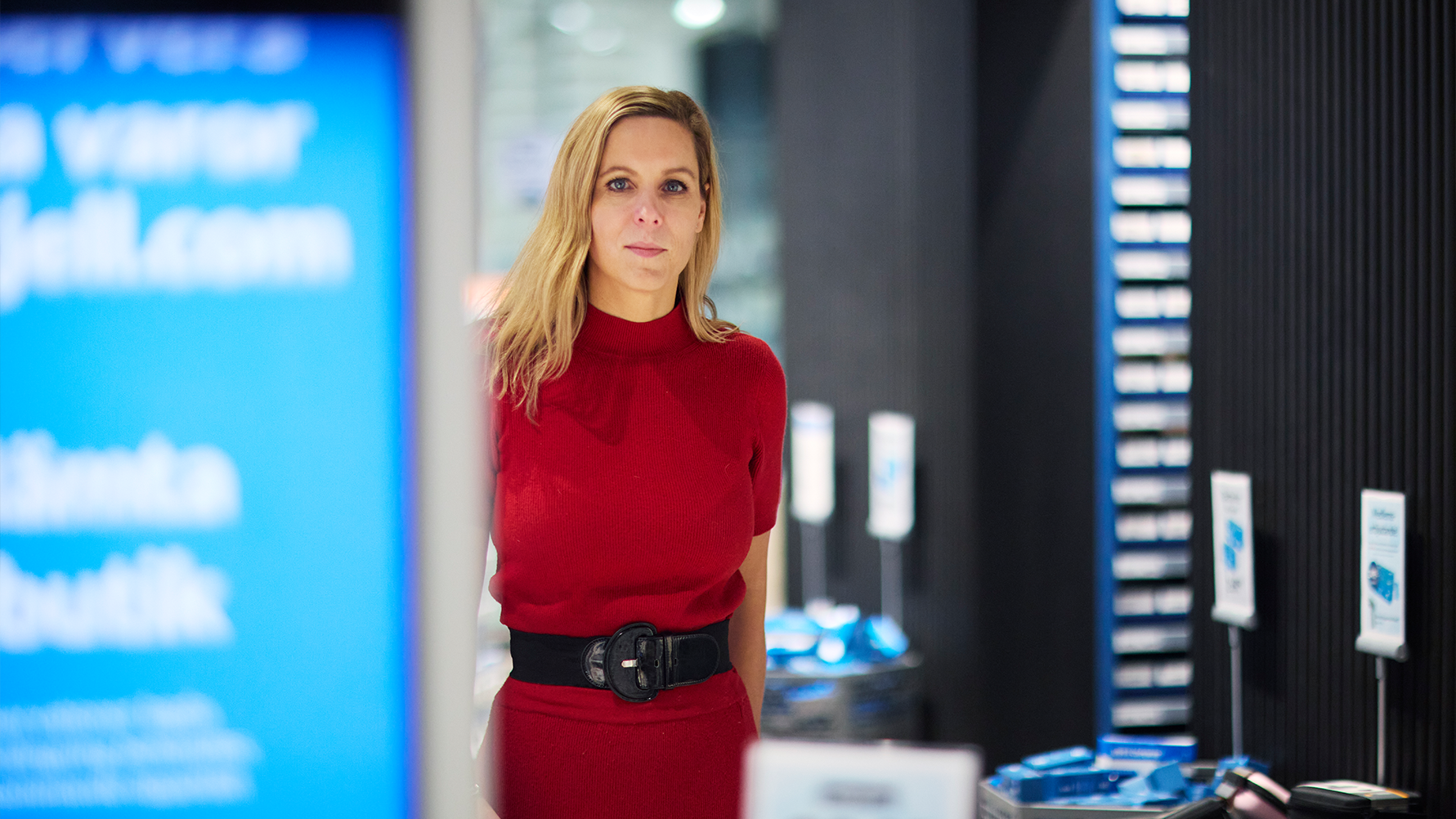Porträtt av en kvinna i röd tröja i en modern kontorsmiljö med blå belysning