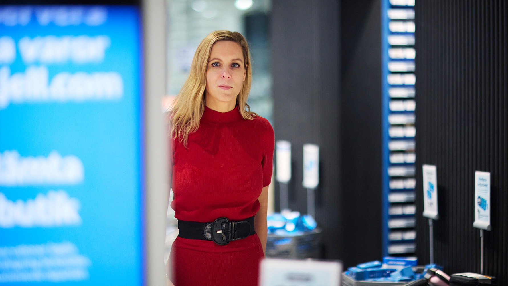 Porträtt av en kvinna i röd tröja i en modern kontorsmiljö med blå belysning