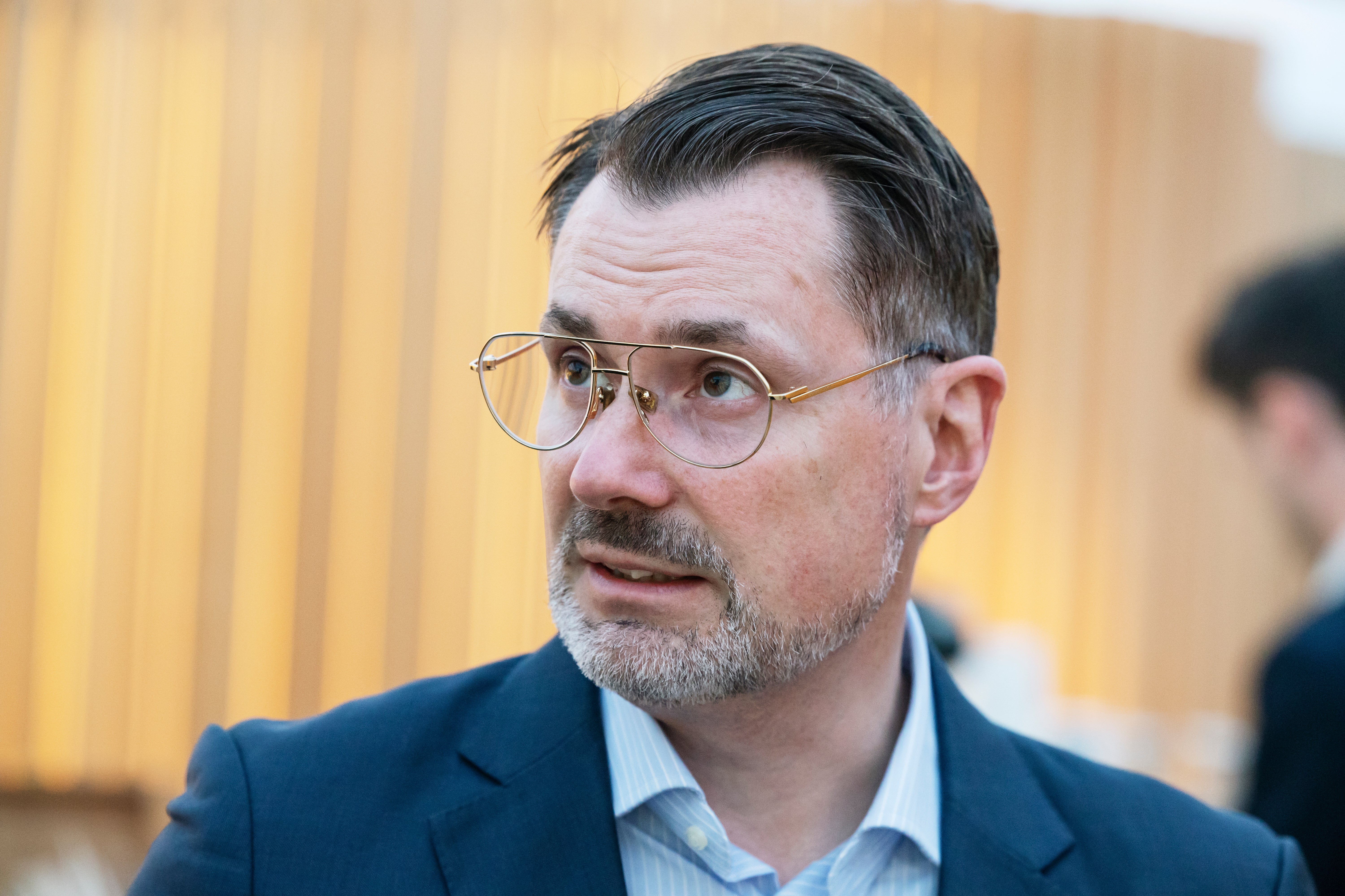Porträtt av en man i kavaj och glasögon som tittar åt sidan.