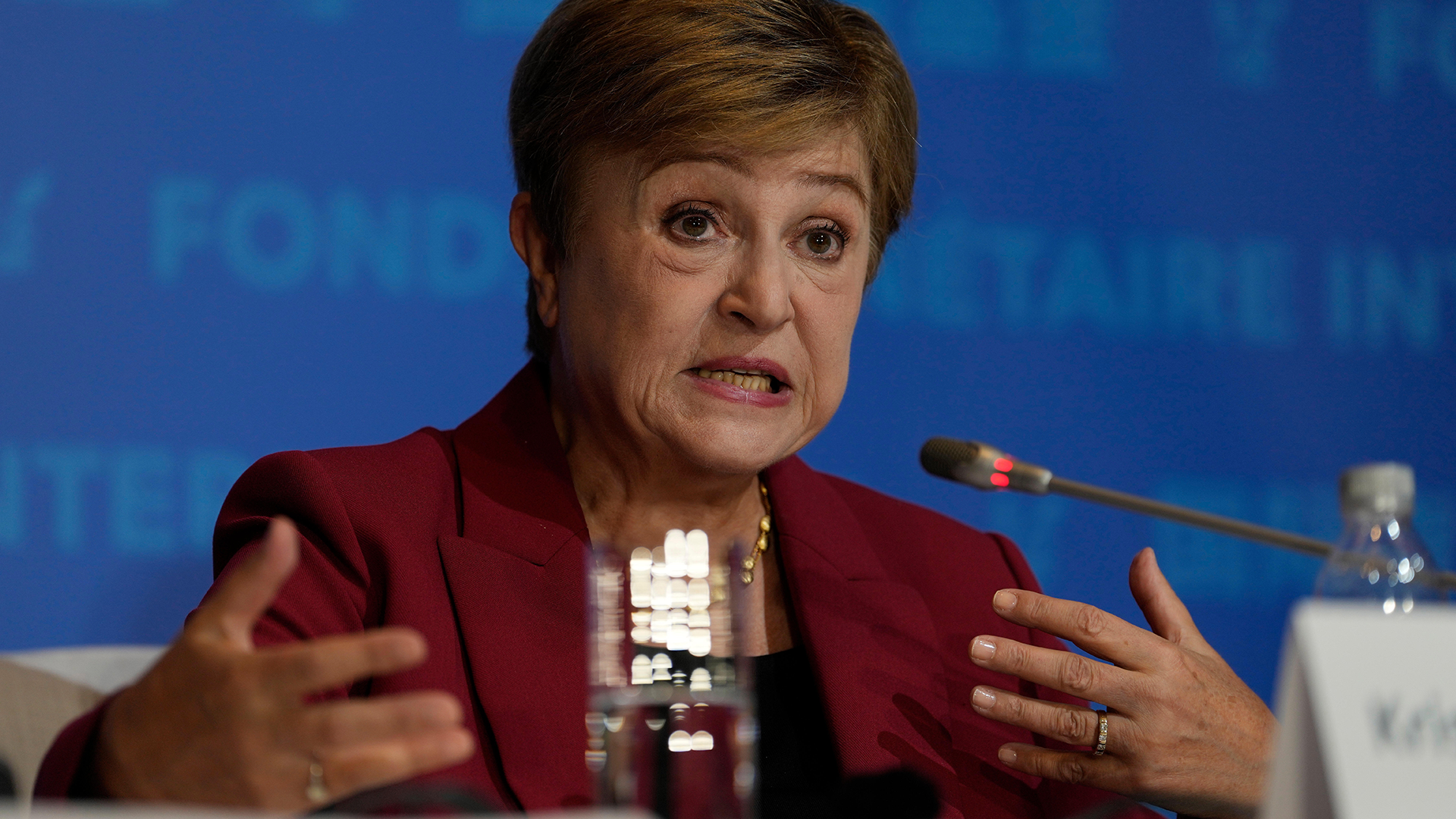 Kvinna i vinröd kavaj talar vid en mikrofon under en konferens