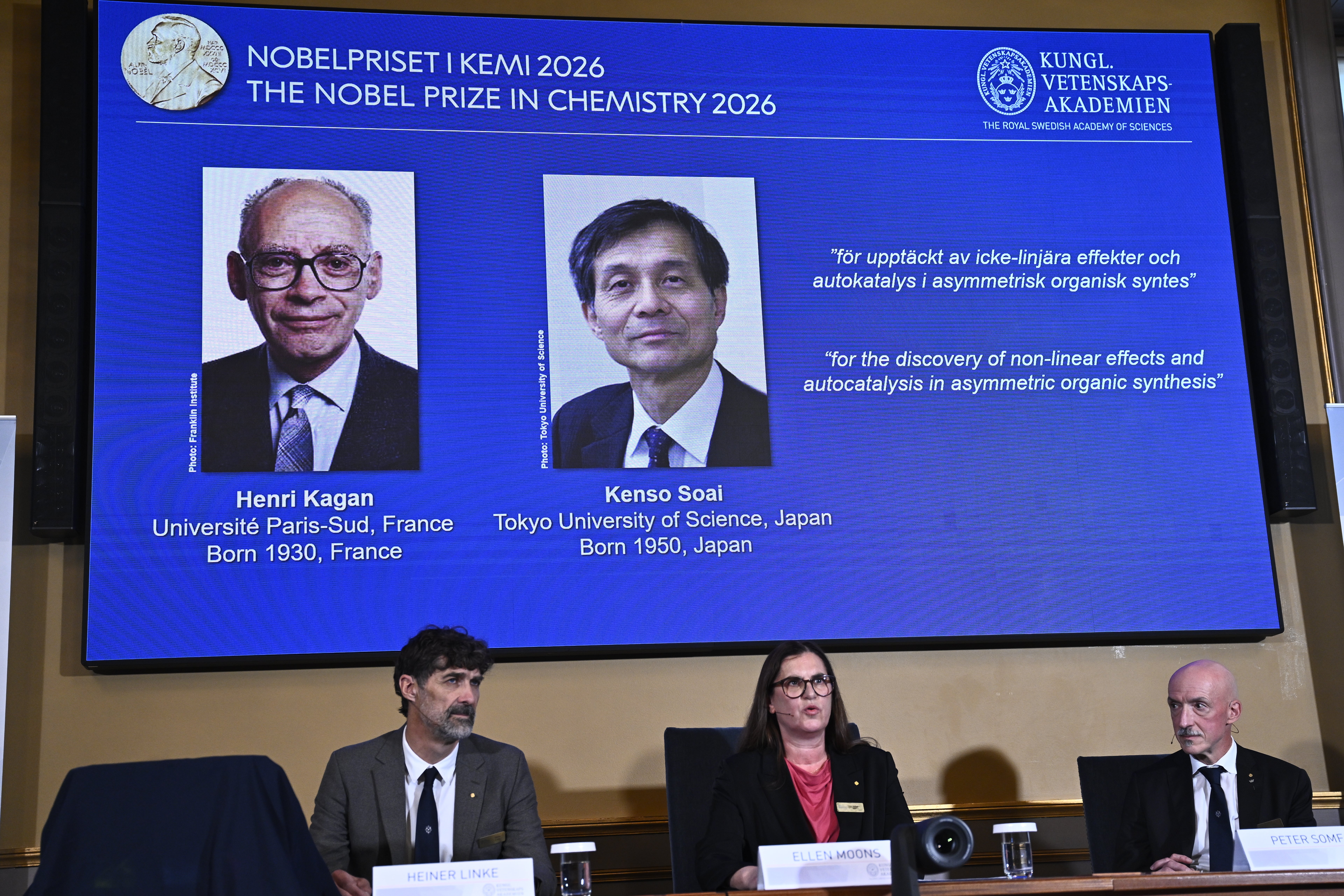 Tre personer sitter vid ett bord framför en stor skärm som visar två Nobelpristagare i kemi 2026, Henri Kagan och Kenso Soai.