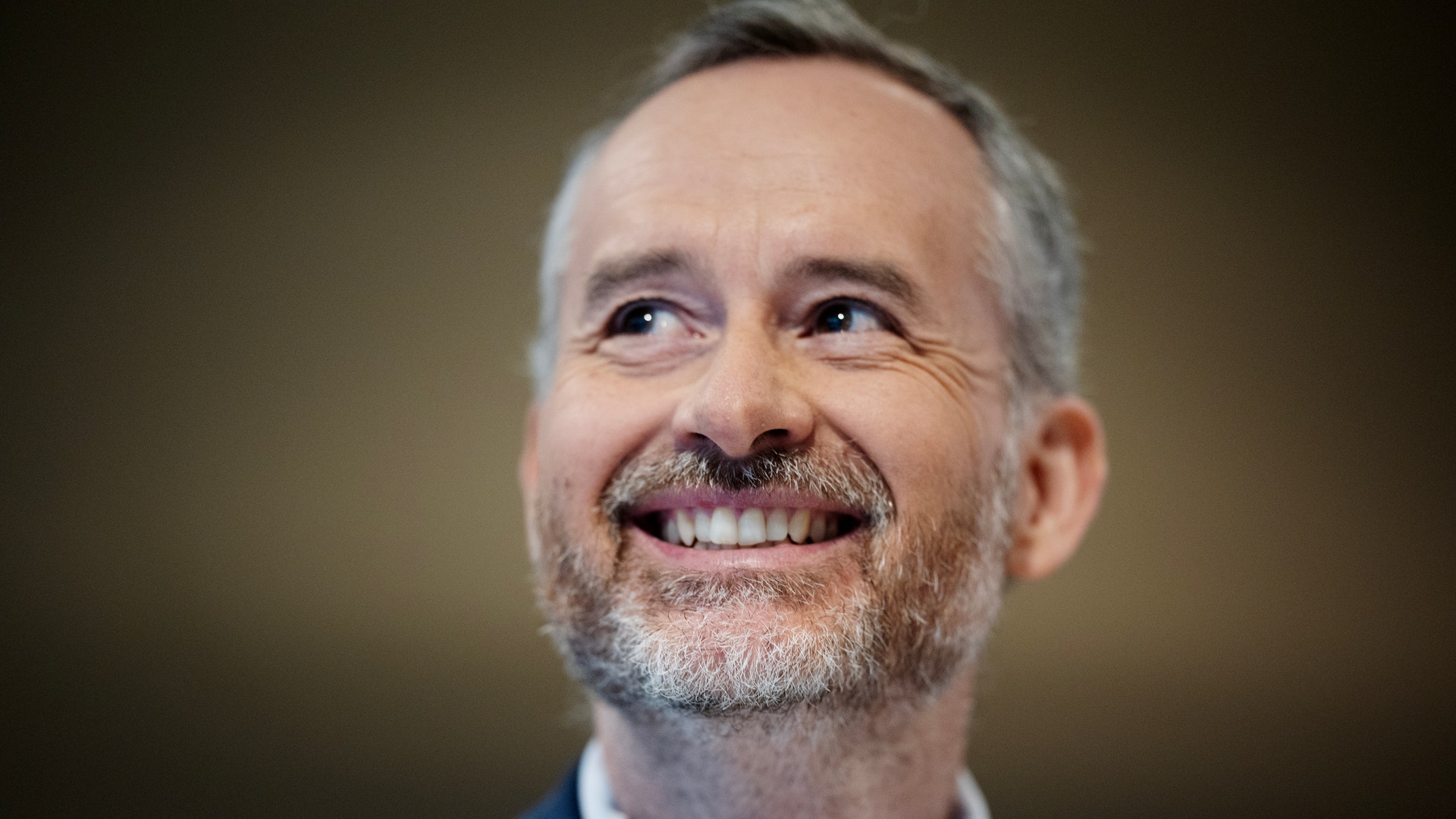 Porträtt av en man i mörk kostym som ler mot kameran.