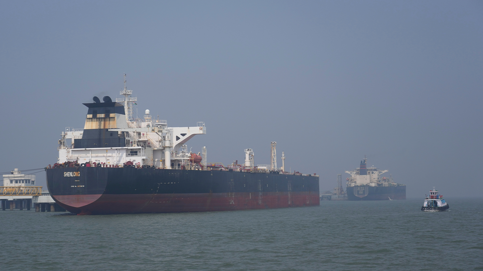 Stora oljetankfartyg ankrade i hamn med industriell infrastruktur i bakgrunden