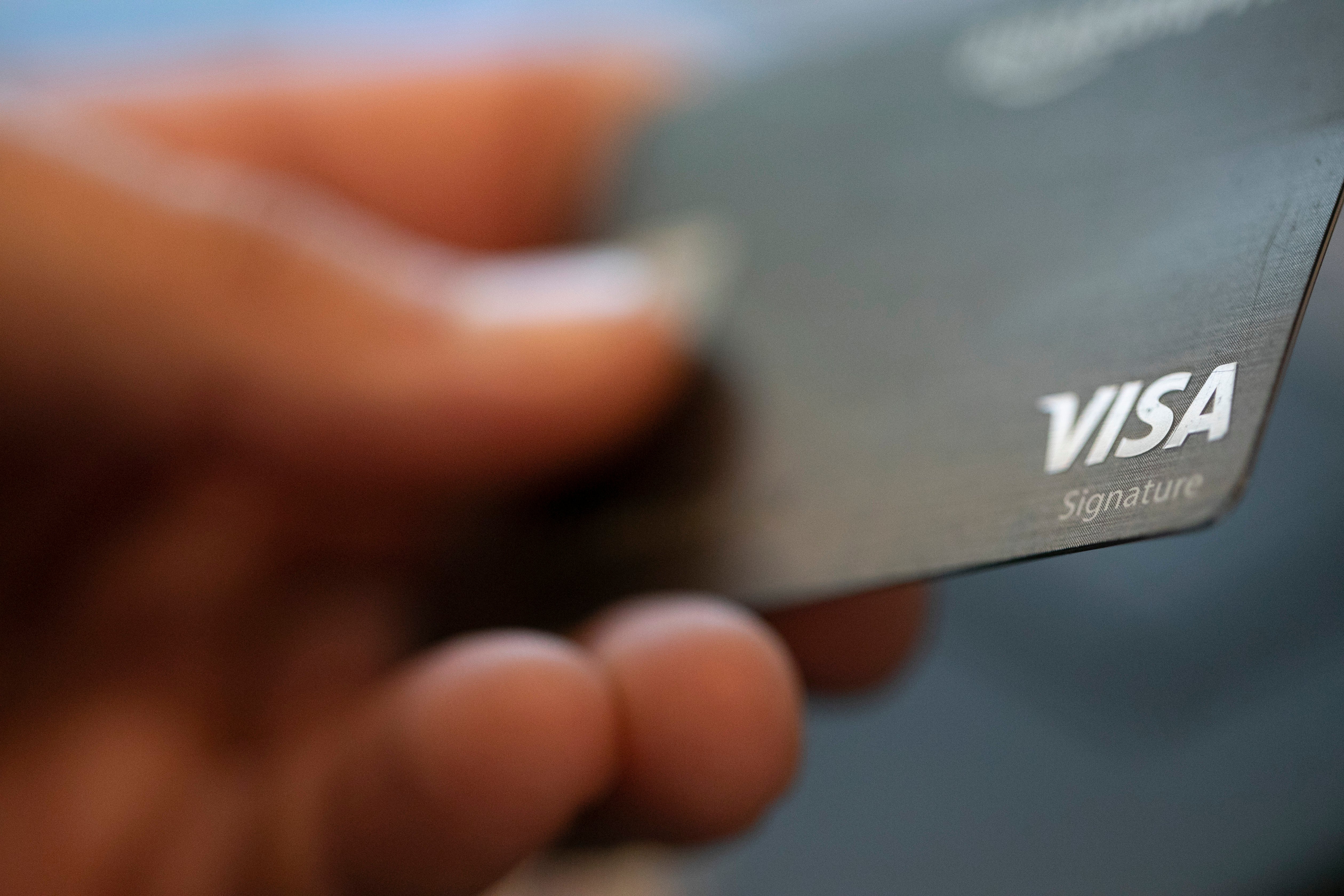 En hand håller ett Visa-kreditkort.