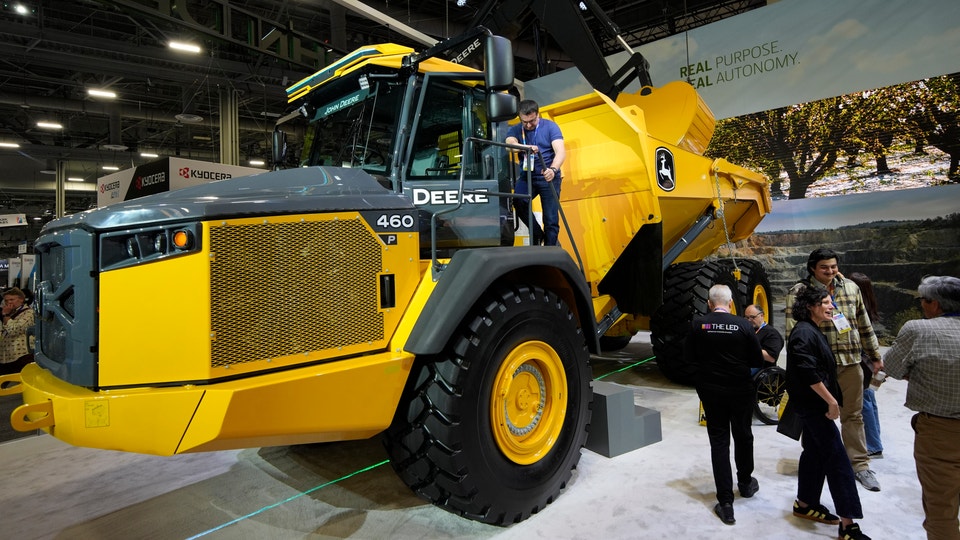 Gul och svart John Deere-lastbil på utställning med besökare