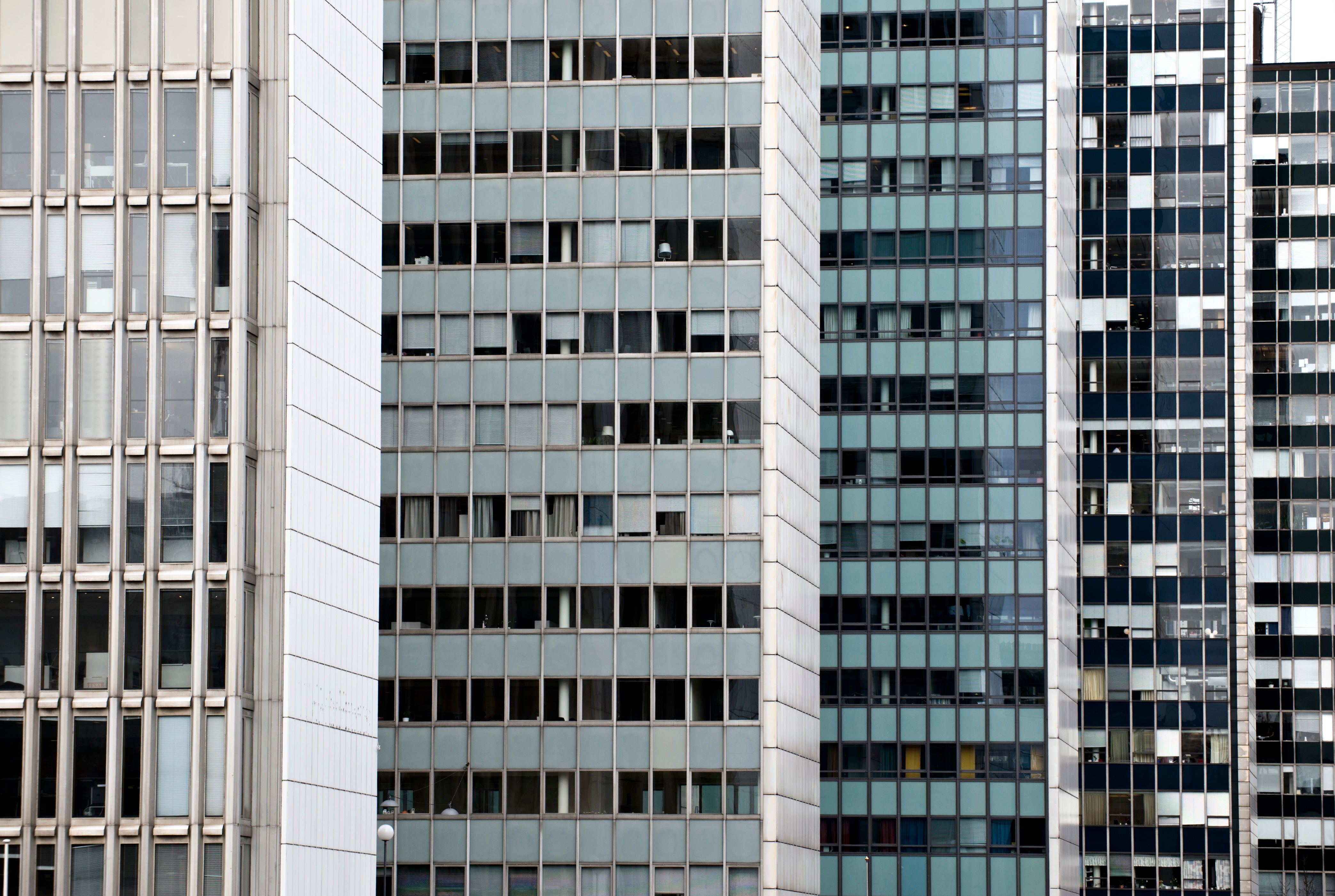 Flera moderna kontorsbyggnader med fasader av glas och betong, med ett regelbundet mönster av fönster i grått, vitt och blått.