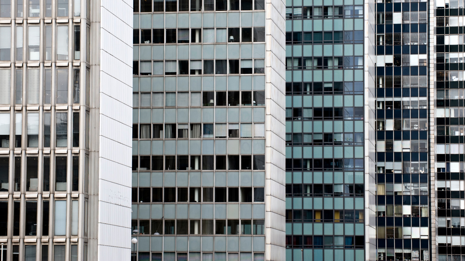 Flera moderna kontorsbyggnader med fasader av glas och betong, med ett regelbundet mönster av fönster i grått, vitt och blått.