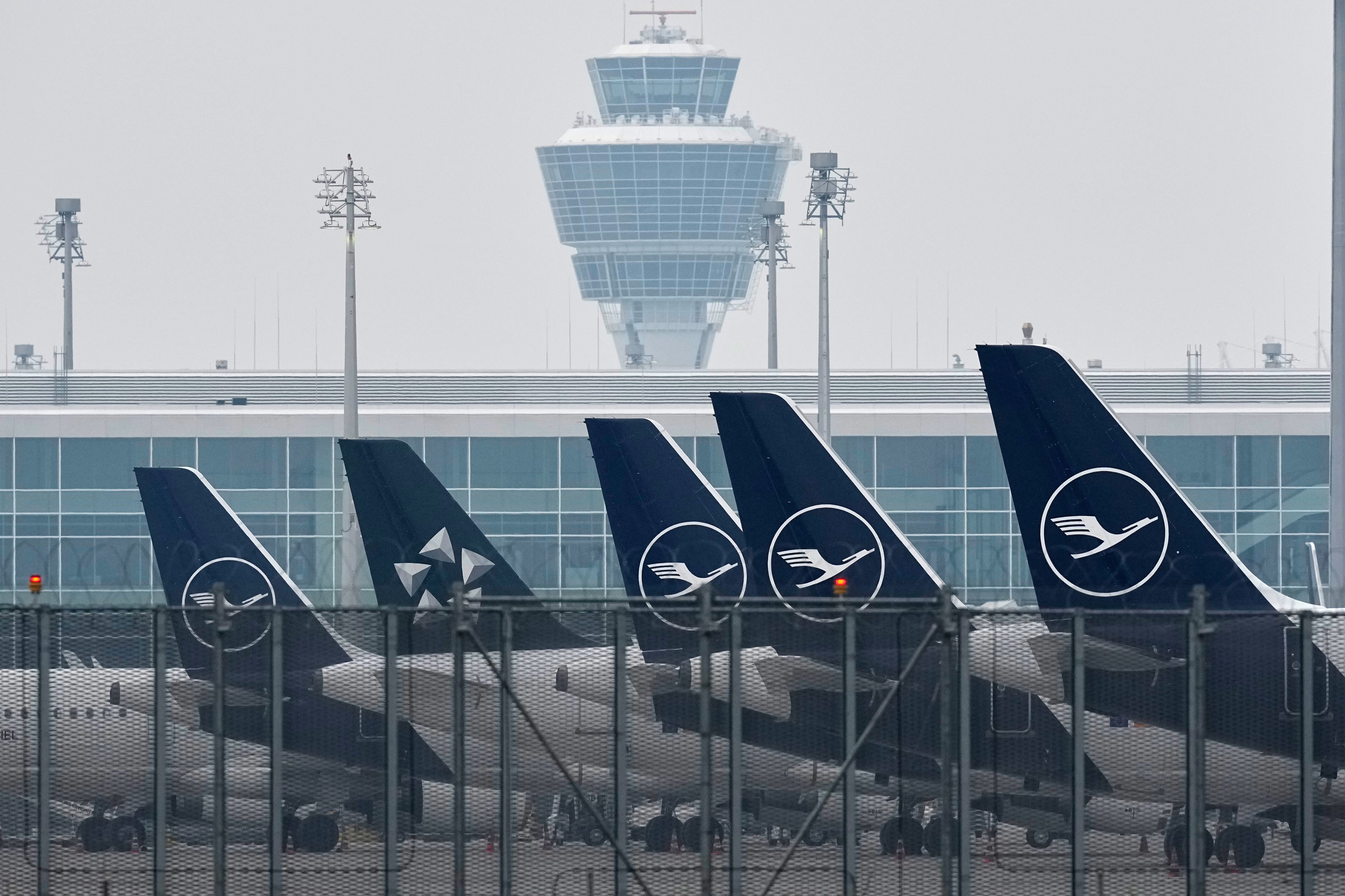 Flera flygplan parkerade vid en flygplats med en terminalbyggnad i bakgrunden.