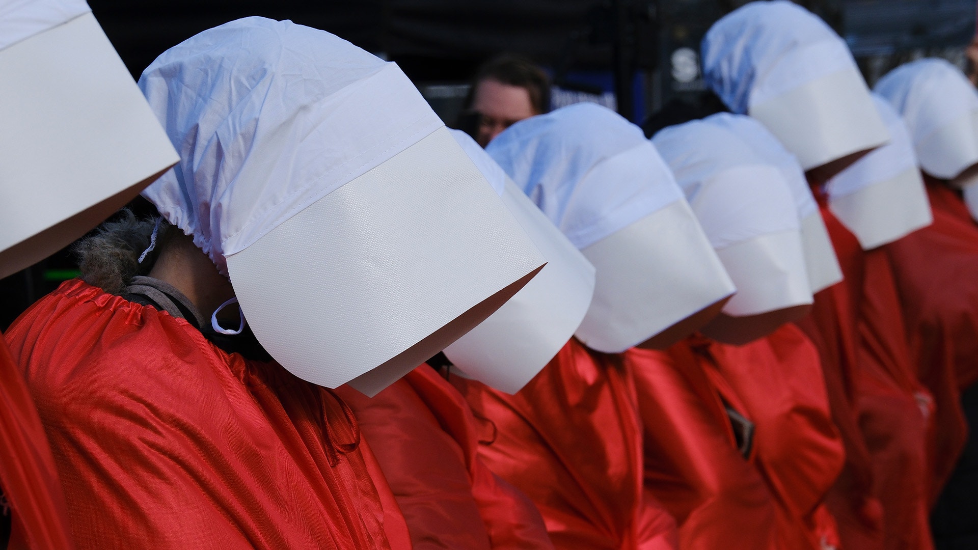 Grupp av personer klädda i röda kläder och vita huvuddukarna.