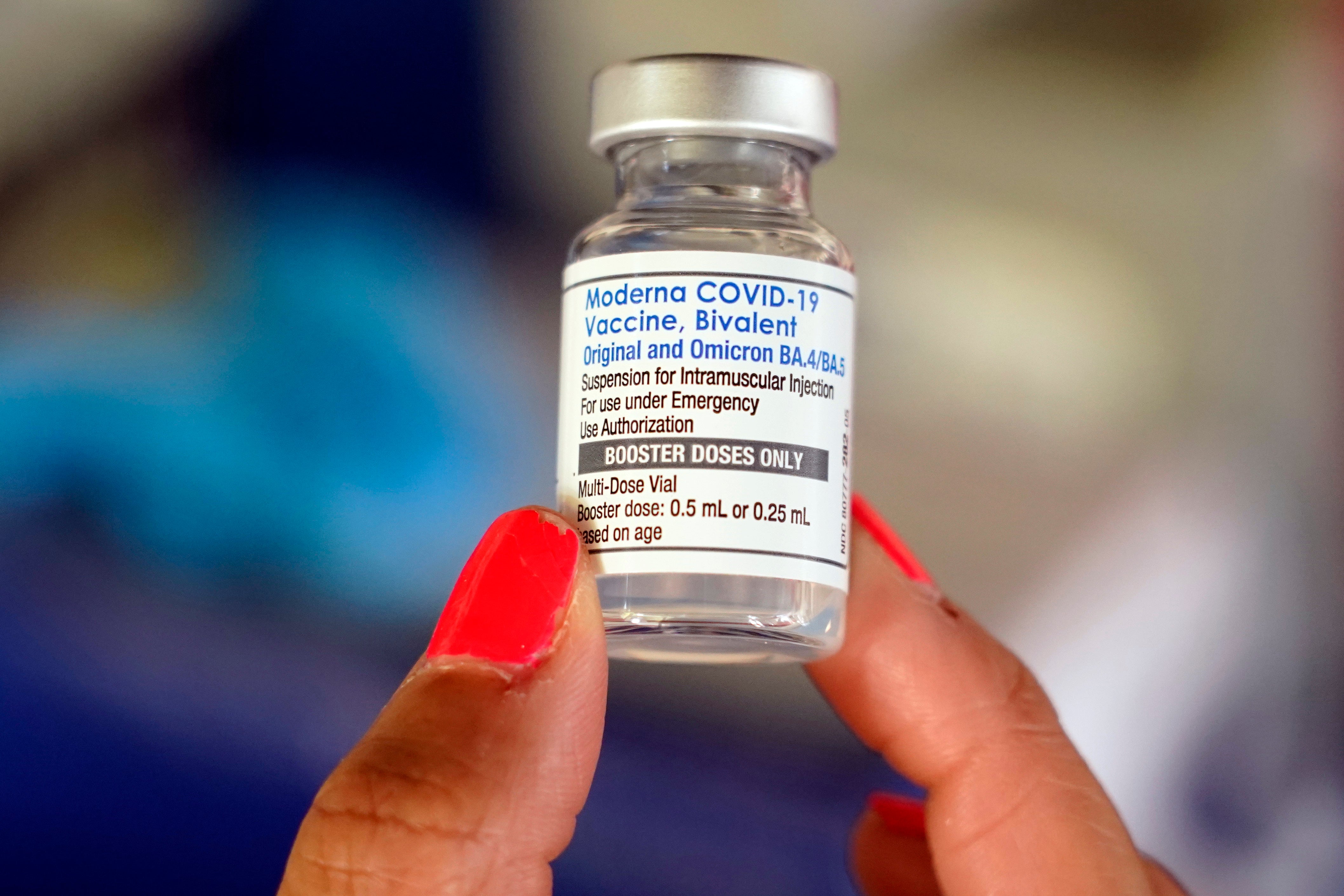 En hand håller upp en vaccinkampanj från Moderna mot COVID-19 med etiketten Bivalent.