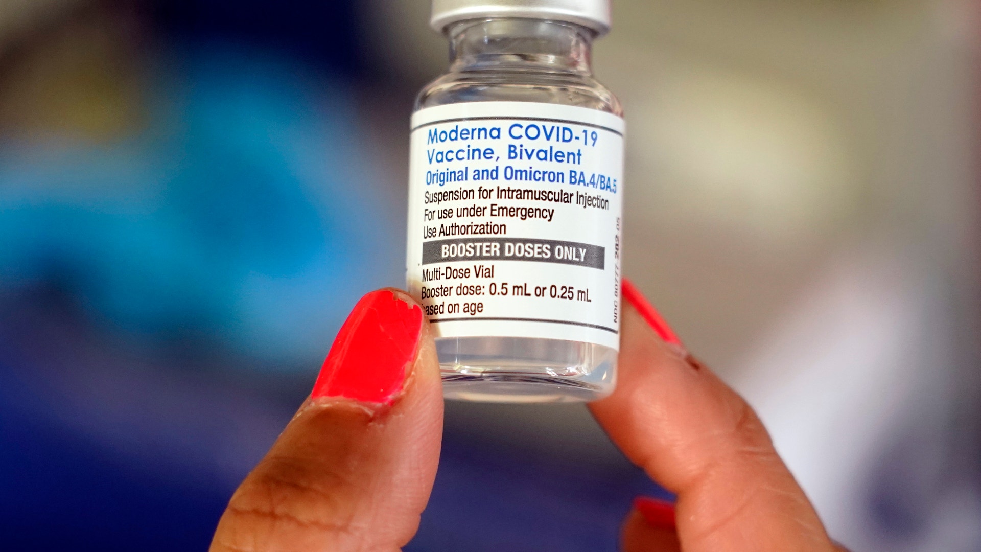 En hand håller upp en vaccinkampanj från Moderna mot COVID-19 med etiketten Bivalent.